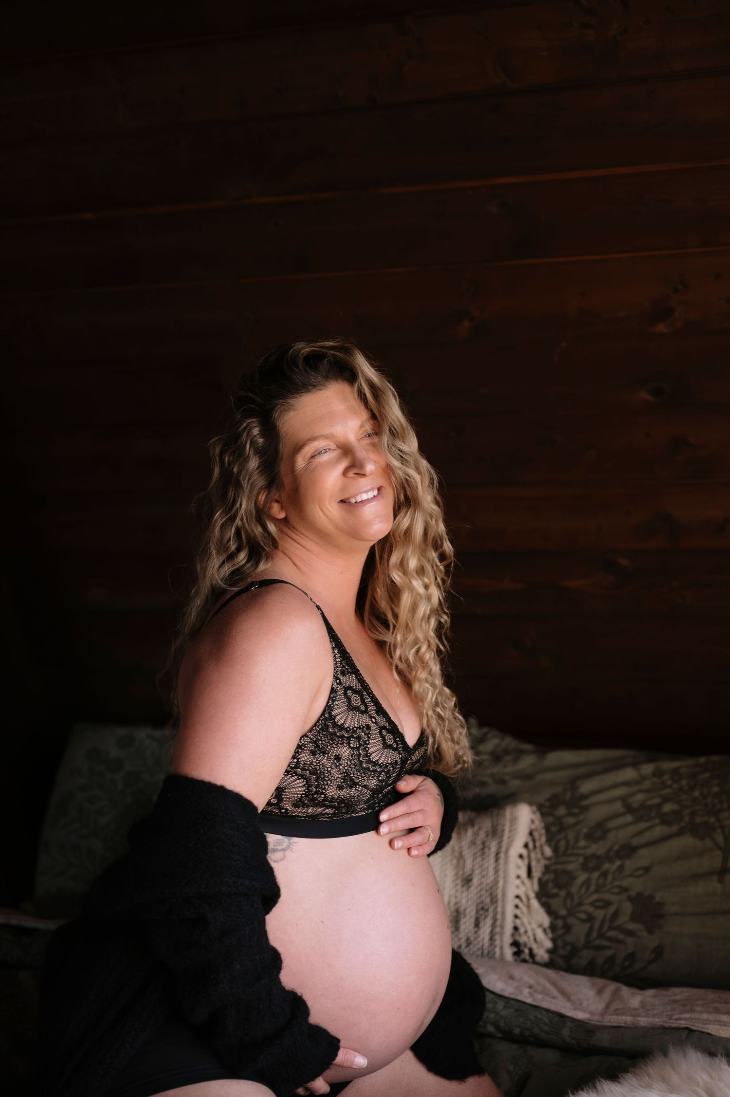 Intimate maternity portraits in black and white featuring soft natural lighting and rustic wooden background.