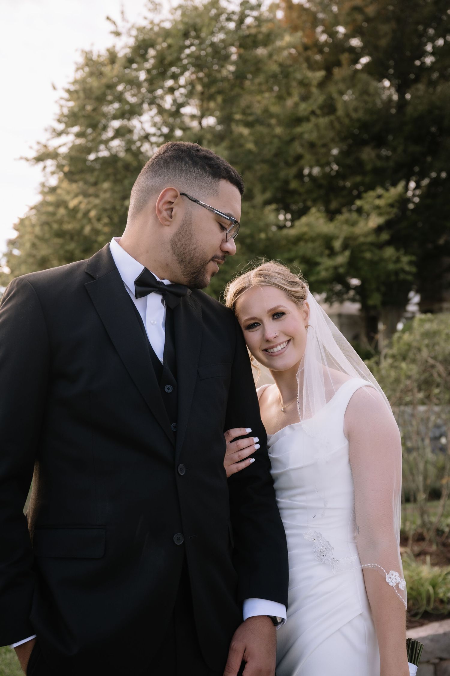 A couple shares intimate moments while posing in an outdoor garden setting during their wedding day.