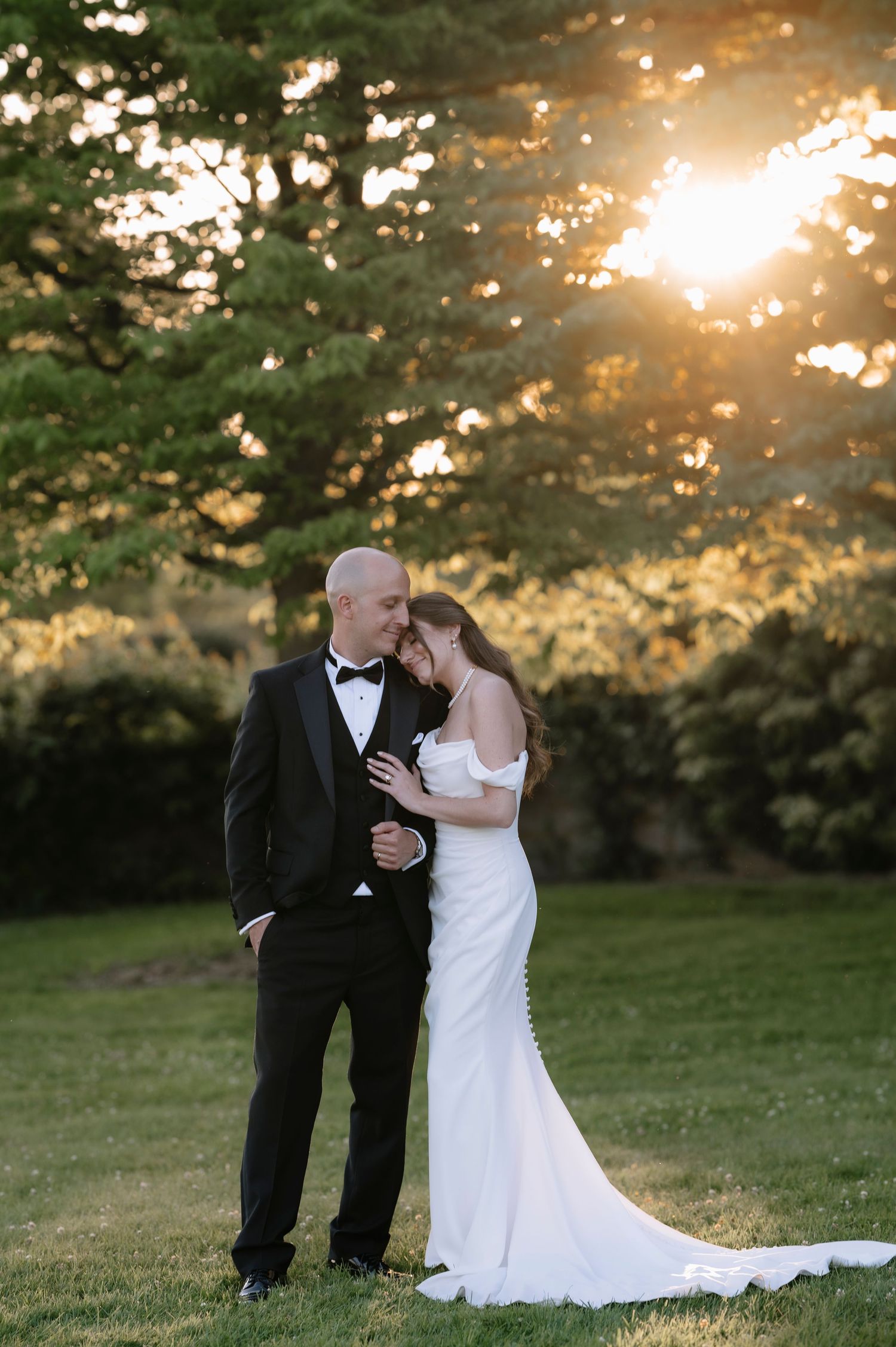 Romantic sunset wedding photography session in a lush green park setting with soft golden light filtering through trees.