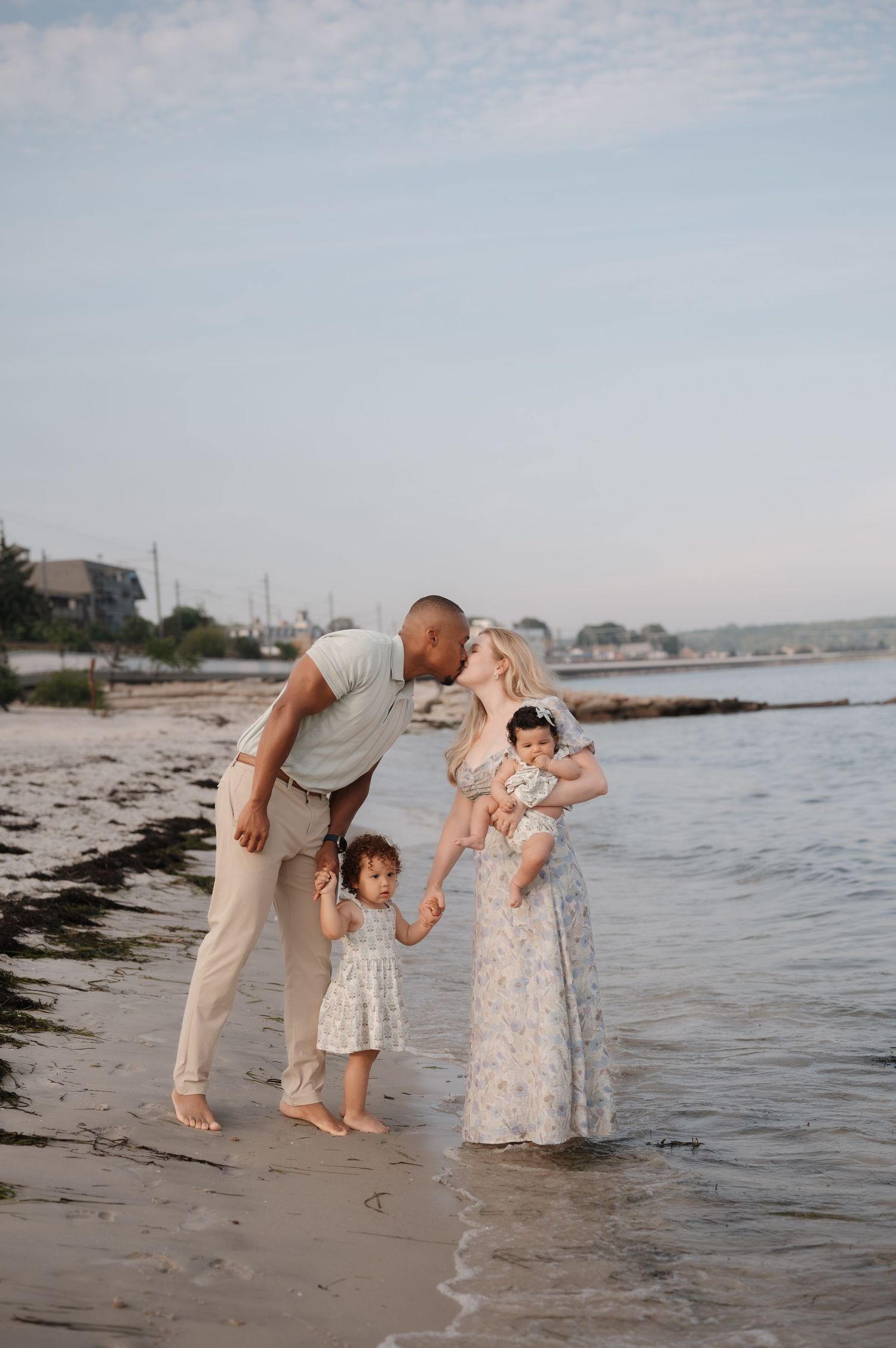 A family enjoys a playful moment together at the beach during sunset, splashing in the shallow water along the shore.
