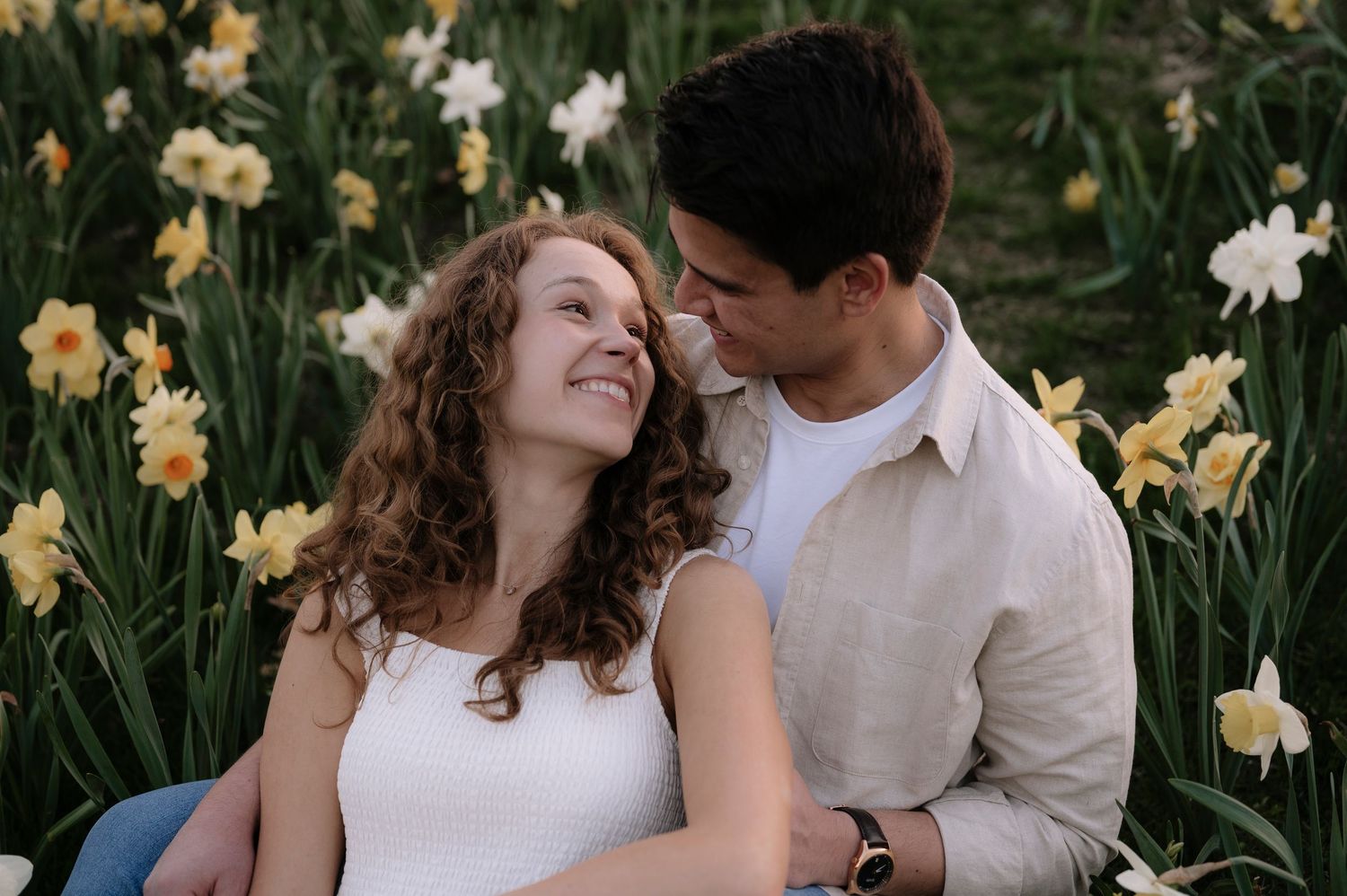 Loving couple sharing joyful moment in field of yellow and white daffodils.
