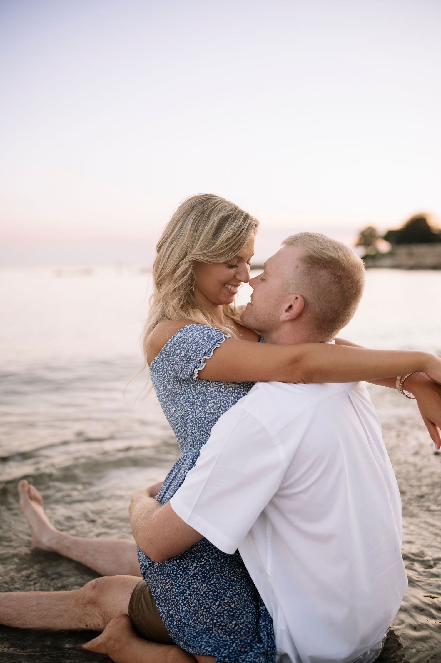 A tender beach moment at sunset with gentle waves in the background.