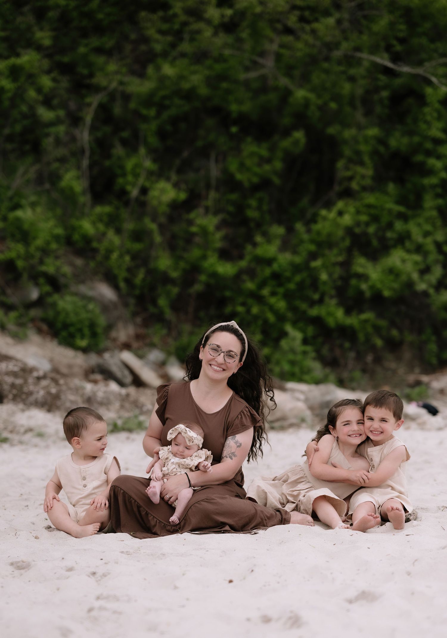 A serene family moment on a sandy beach with lush greenery in the background.