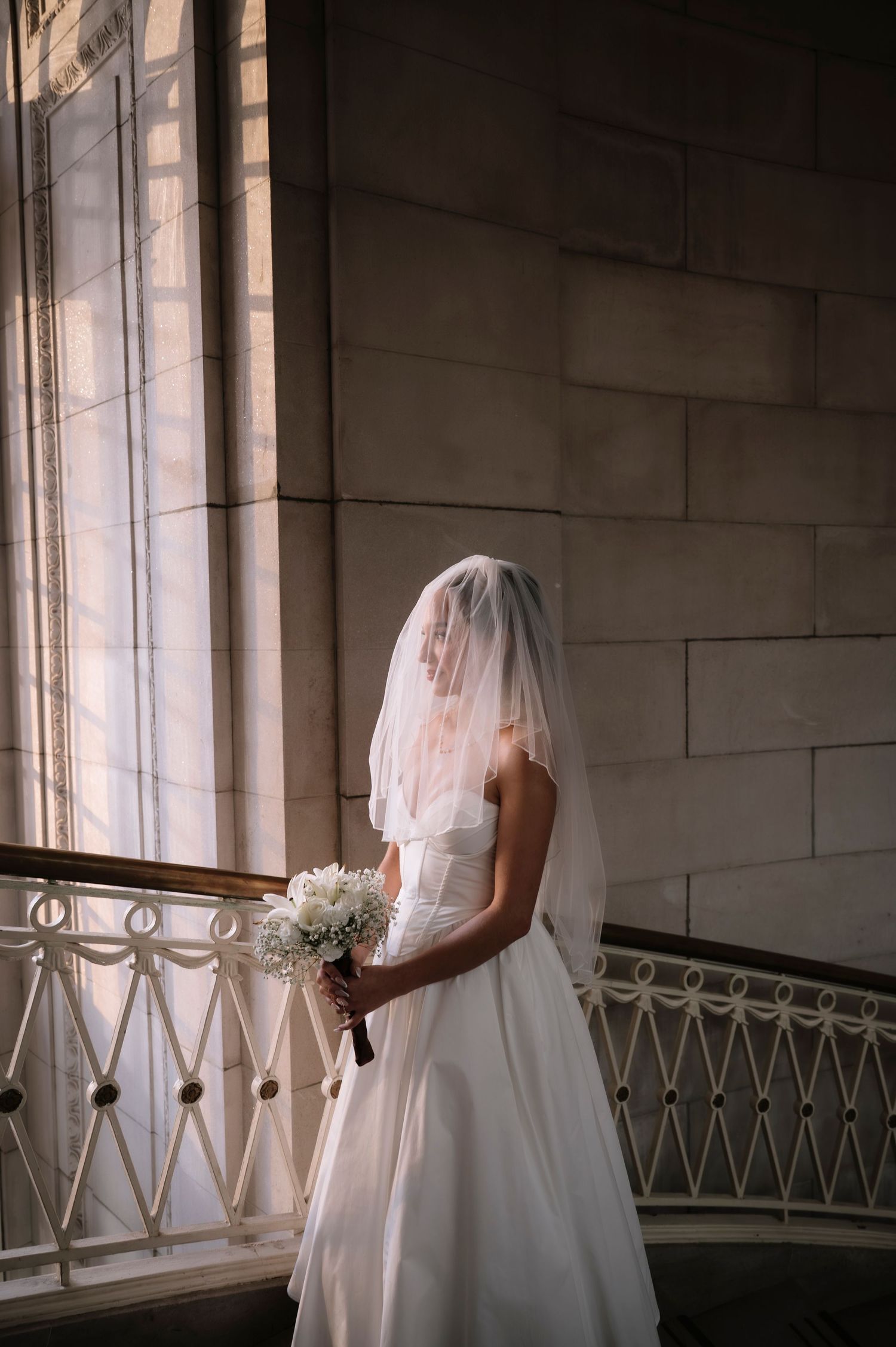 A bride in a white wedding dress and veil stands by a window in a sequence of four similar photos.