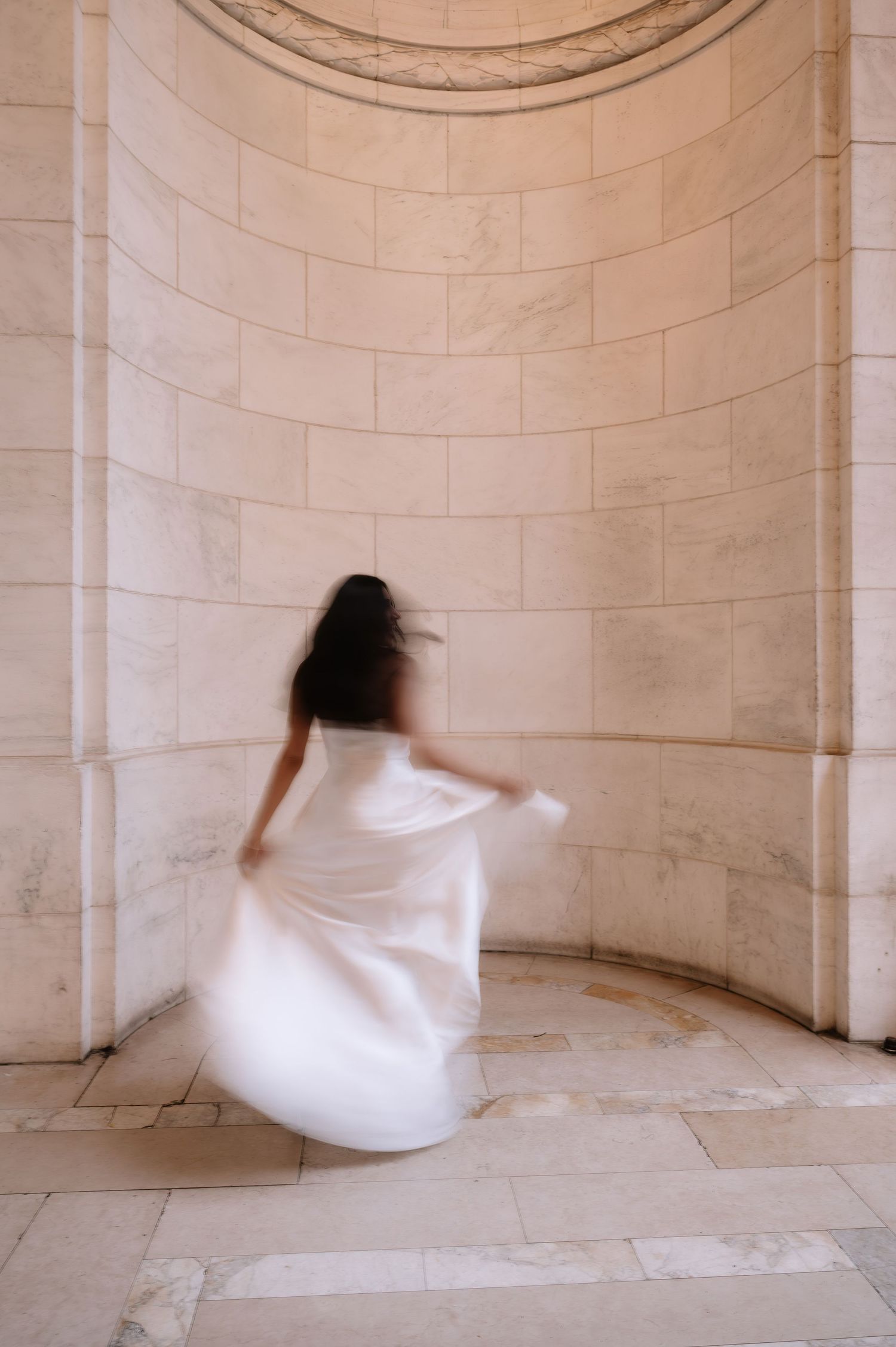 Figure in flowing white dress spins gracefully in curved stone alcove with classical architecture.