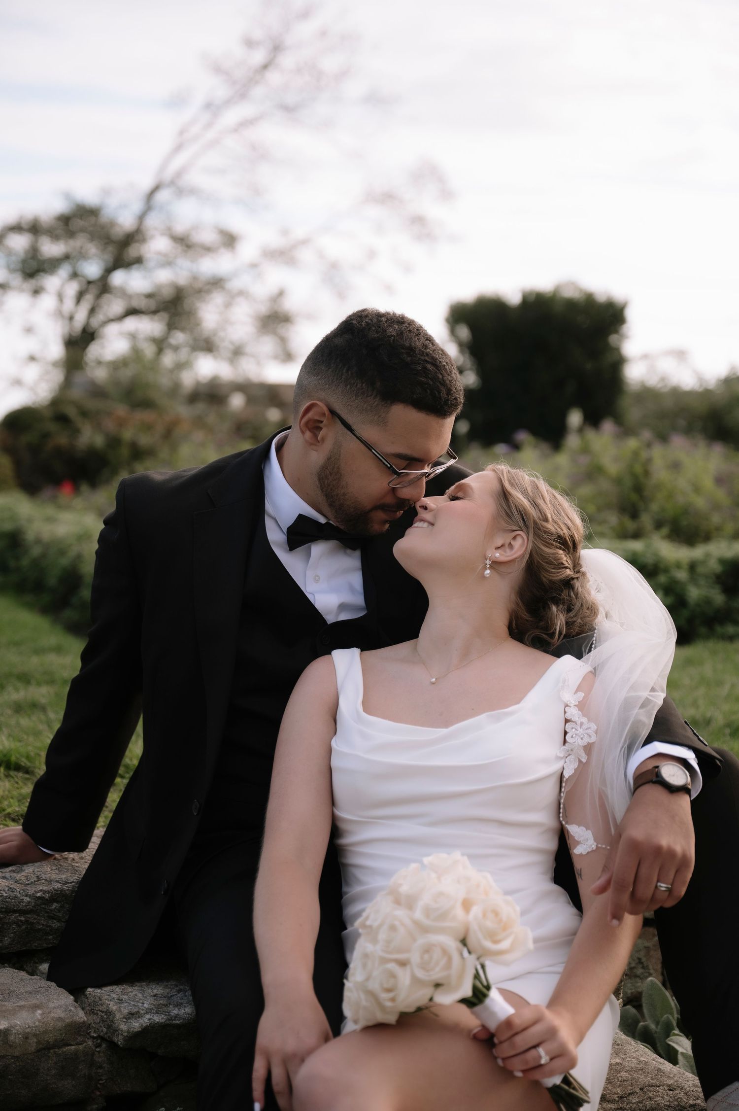 Intimate wedding portrait captured against natural outdoor backdrop during golden hour.