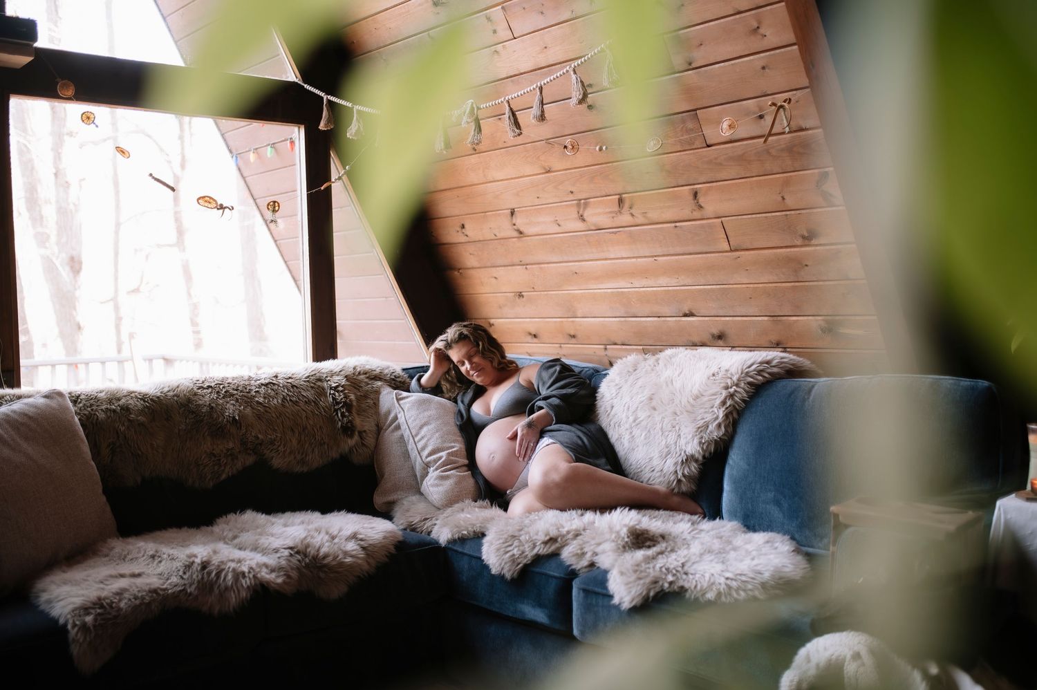 Cozy bedroom interior with exposed brick wall and natural light filtering through plants.