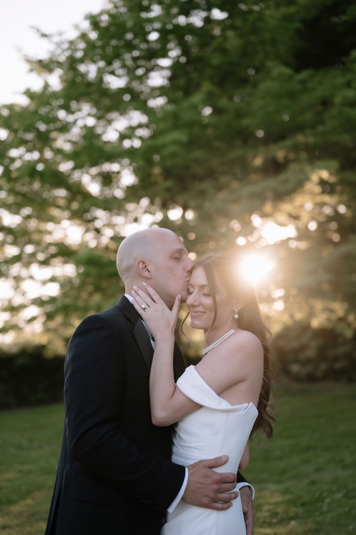 A loving couple shares a romantic embrace during golden hour in a lush outdoor setting.