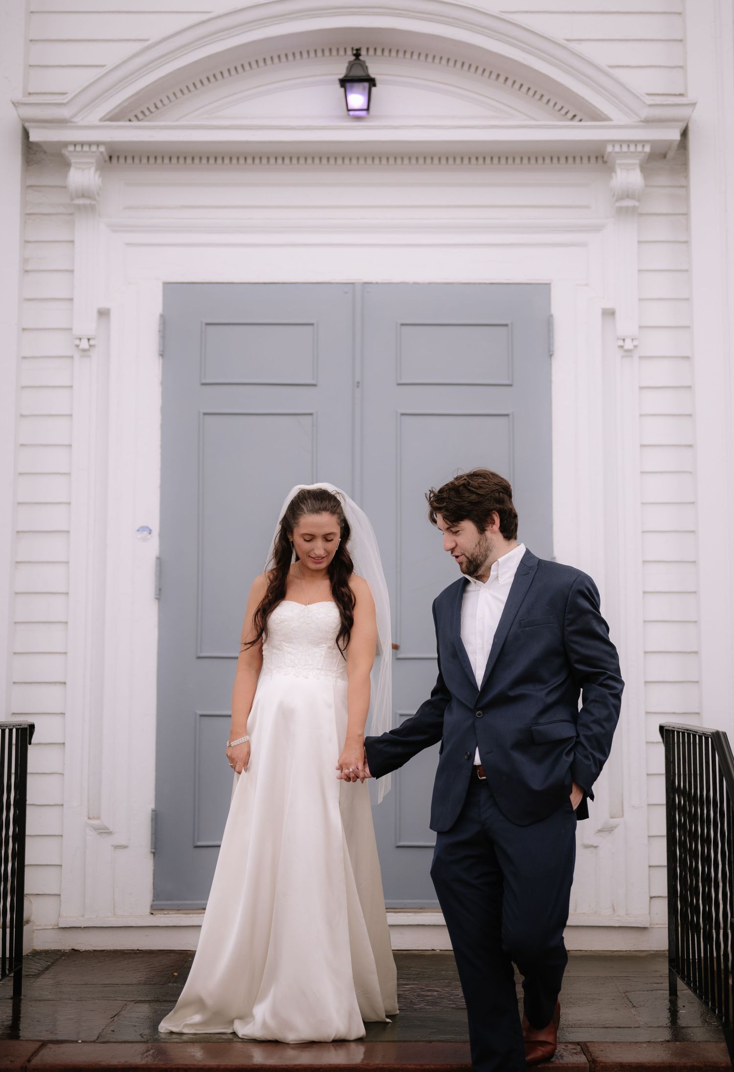 Wedding couple sharing a candid moment in front of elegant gray double doors.