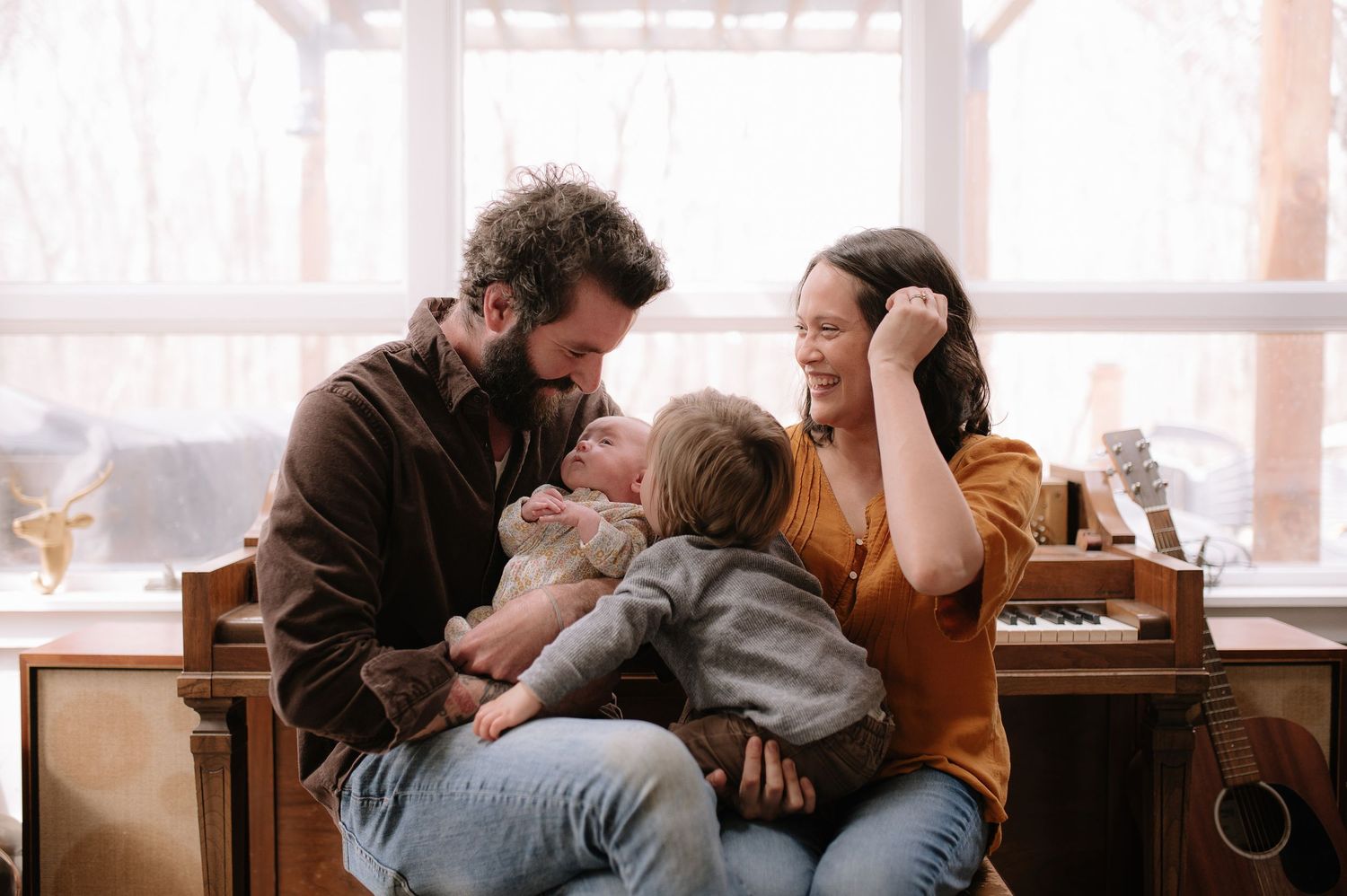 Family sharing an intimate moment together while seated on cushions in a bright indoor space.