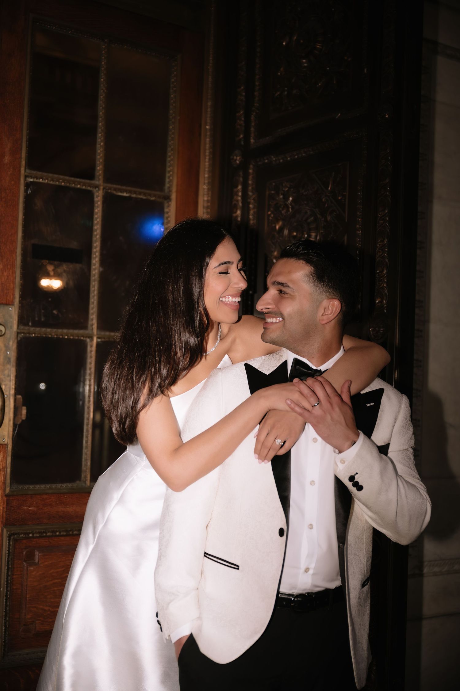 A romantic wedding photo shows a couple dancing and laughing together, with the bride in white and groom in a white jacket.