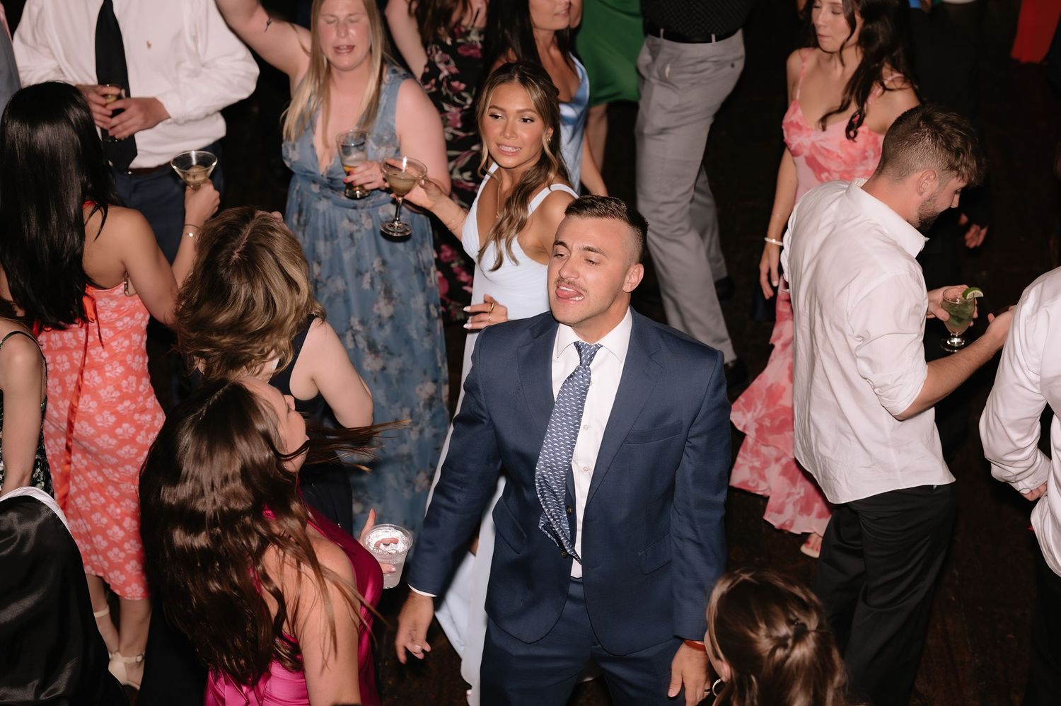 Wedding guests dancing and celebrating on the dance floor at a lively wedding reception party.