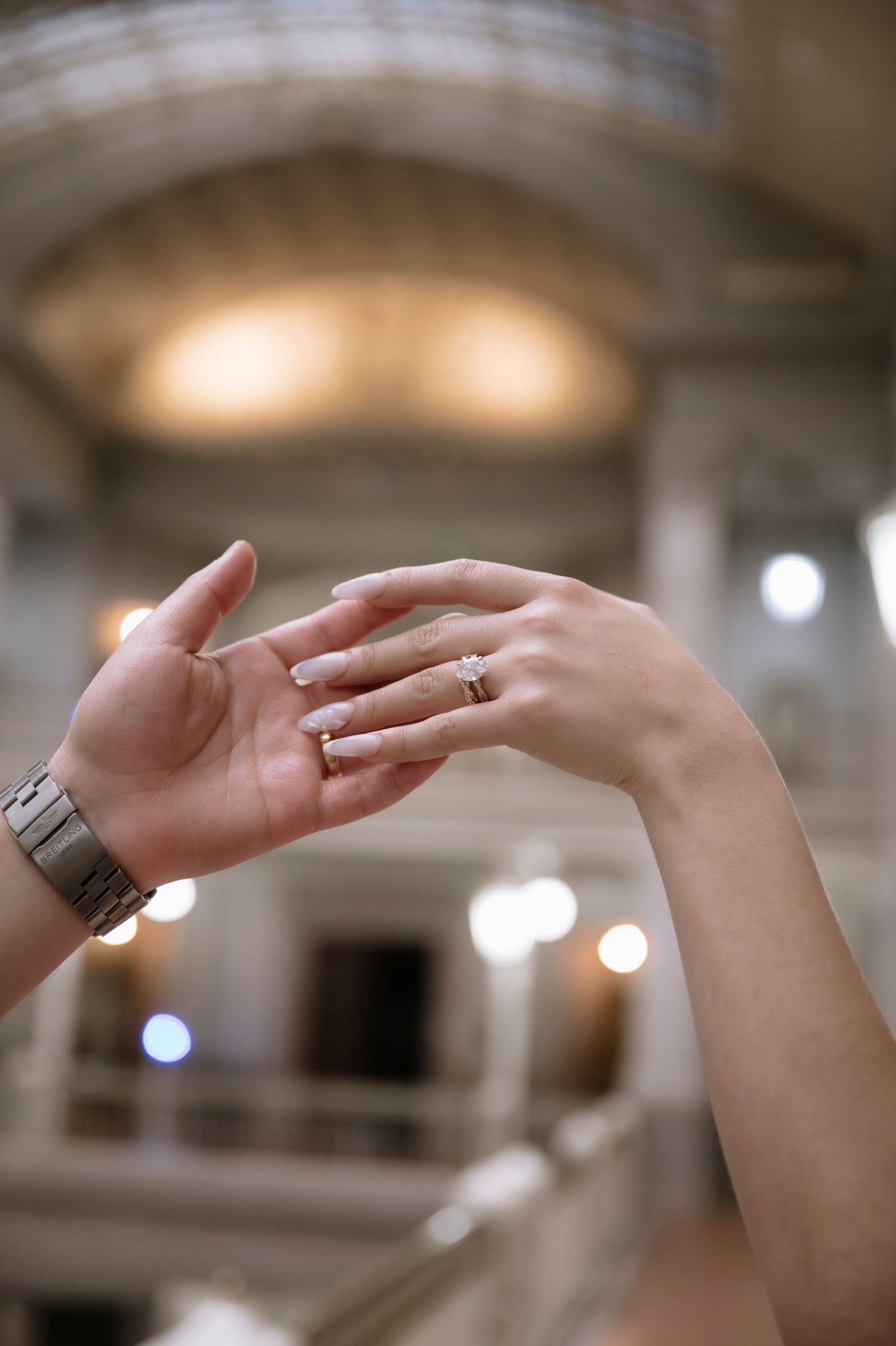 Close-up of hands reaching and intertwining in an elegant dance-like motion with soft lighting in the background.