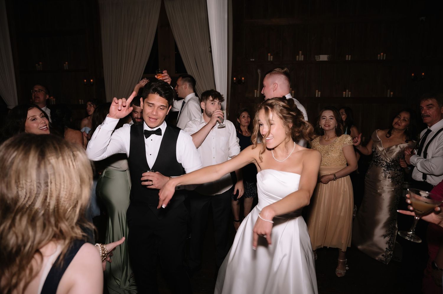 Bride and groom laughing and dancing together at their wedding reception celebration.