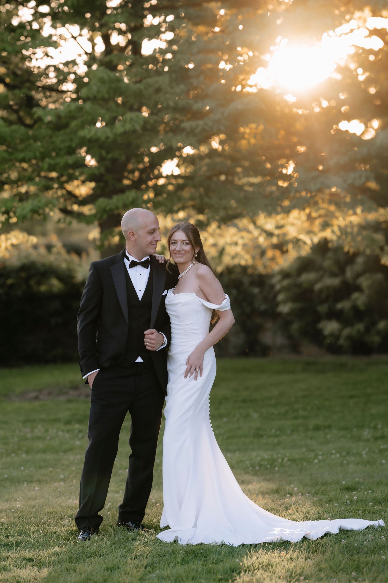 Bride and groom share a romantic moment at sunset in a lush garden setting during their outdoor wedding celebration.