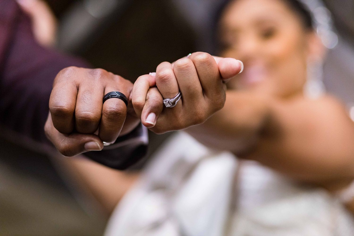 Close-up of hands showing engagement ring in romantic lighting.