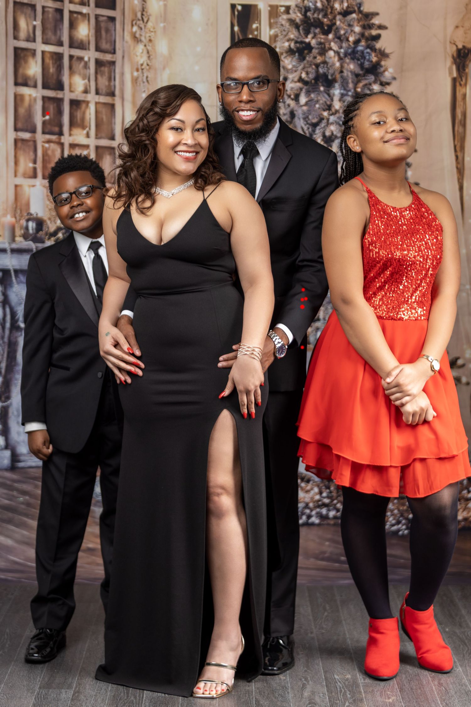 Formal family portrait with elegantly dressed group in front of Christmas decor.