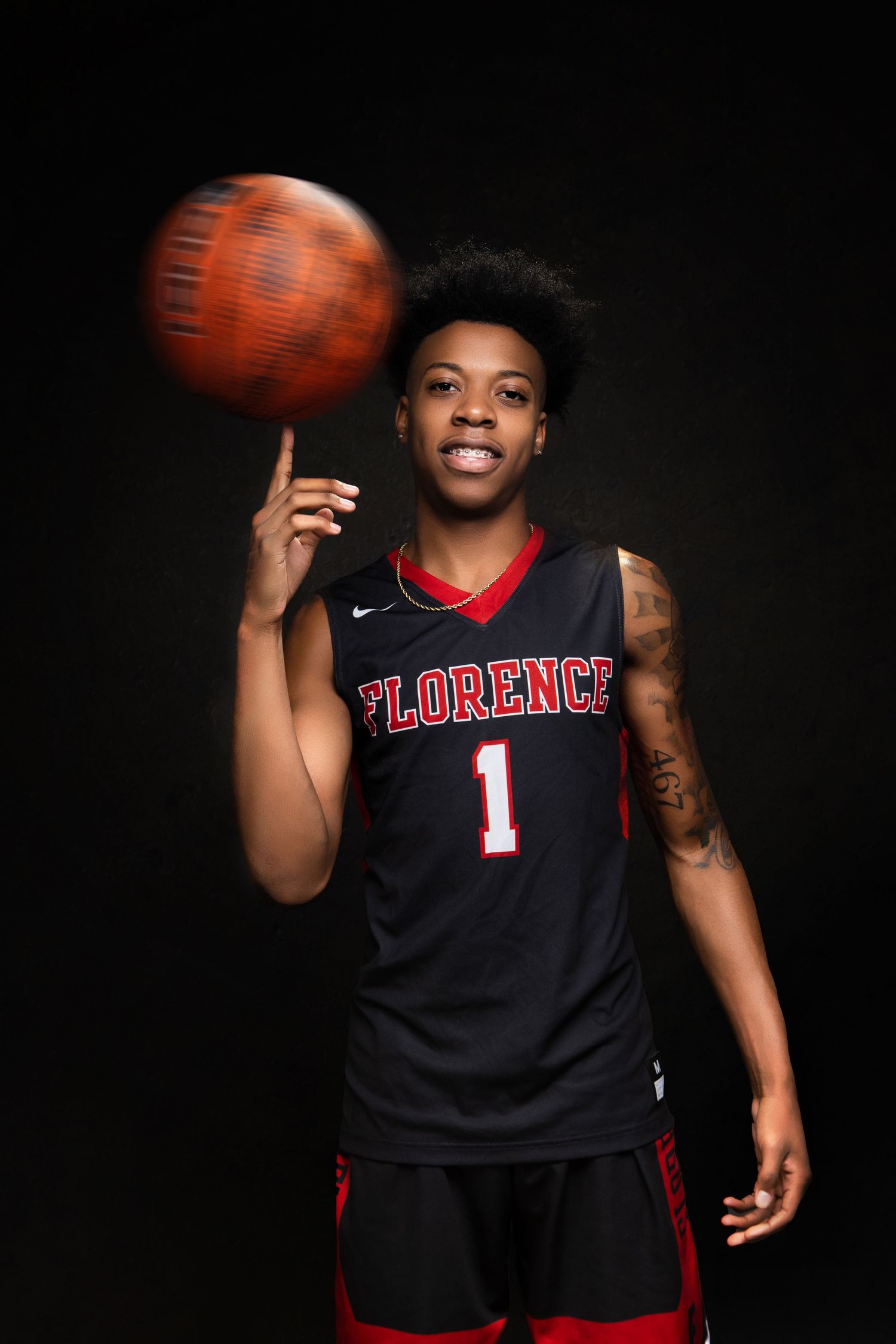 Basketball athlete in Florence uniform spinning ball on finger in dramatic lighting.