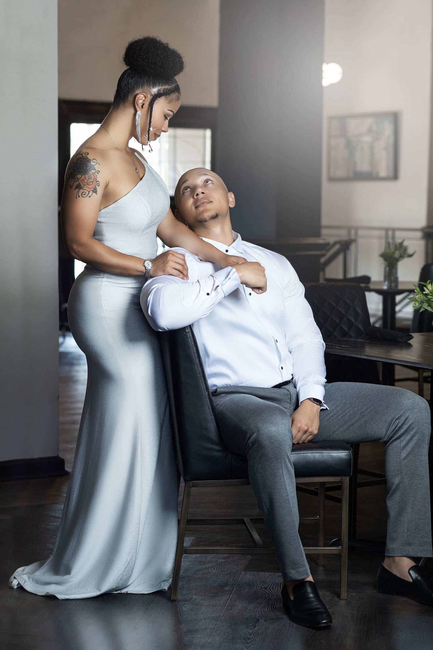 Elegant couple in formal attire sharing an intimate moment in a modern interior setting.