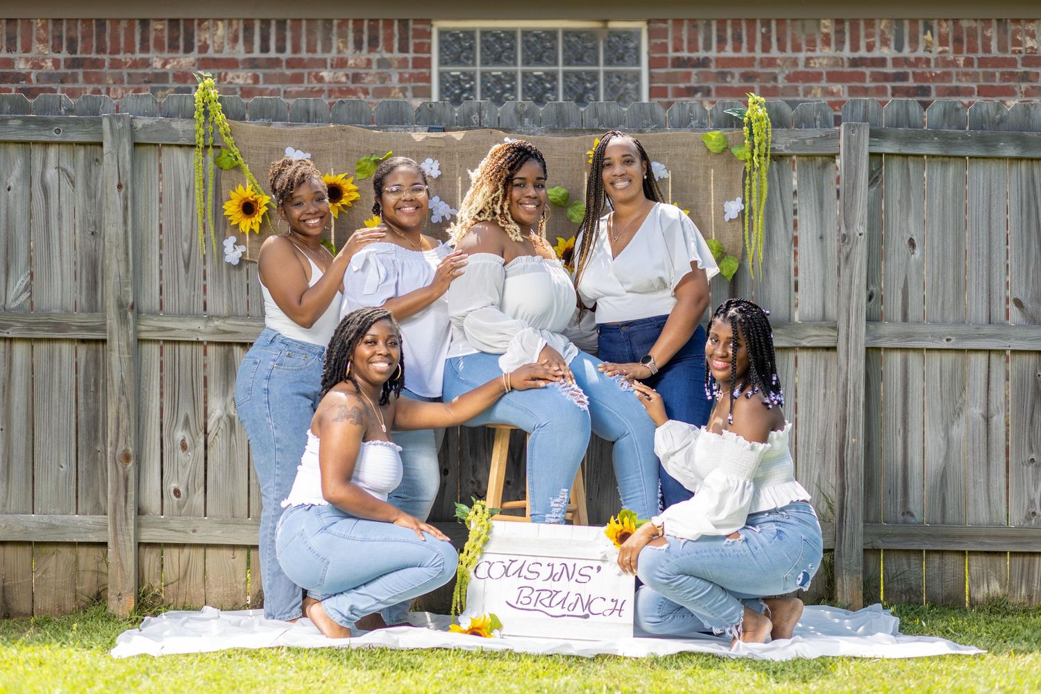Group photo of friends in coordinated white and denim outfits posing outdoors.
