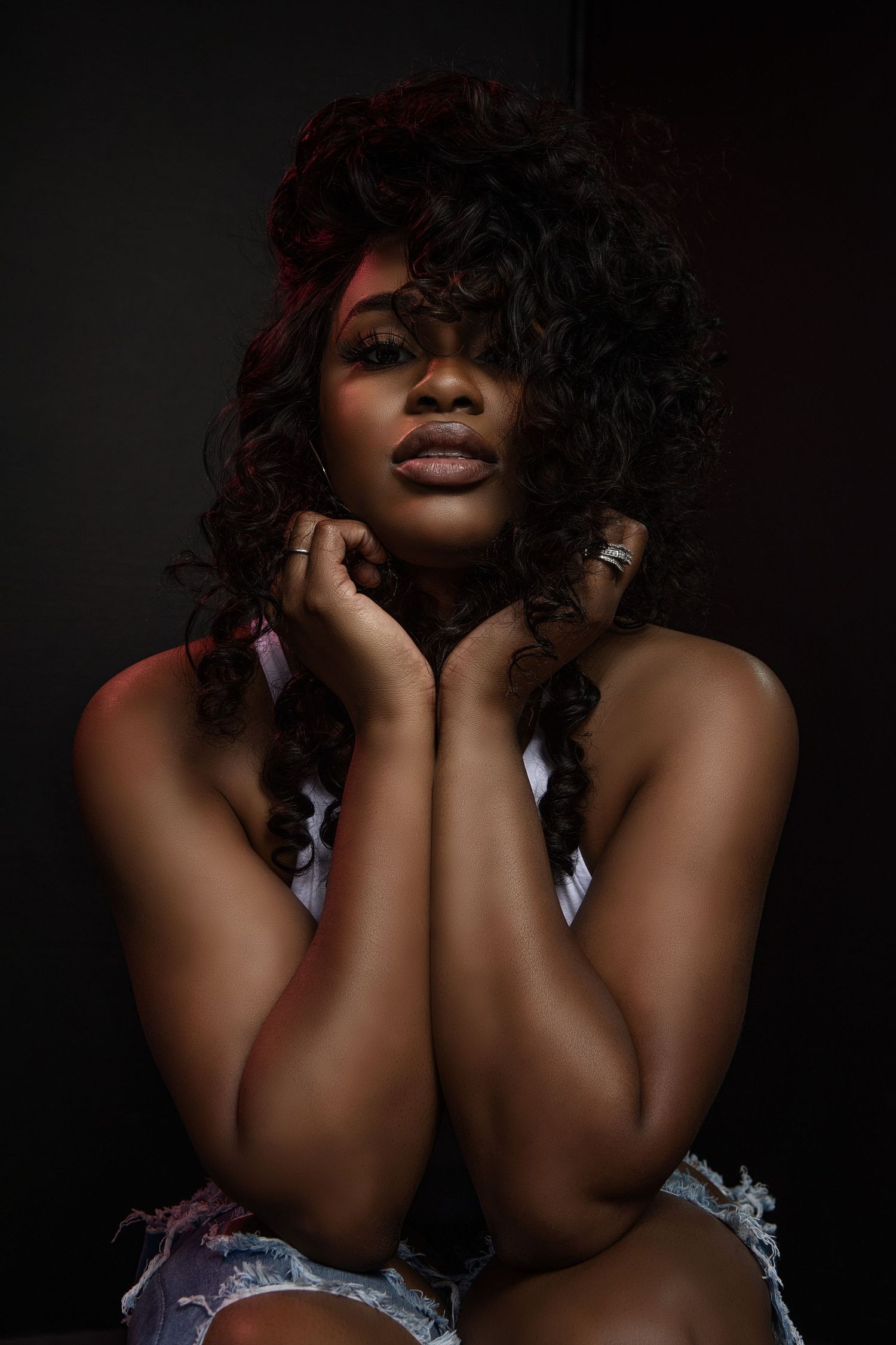 Moody dark portrait with dramatic lighting and curly hair.