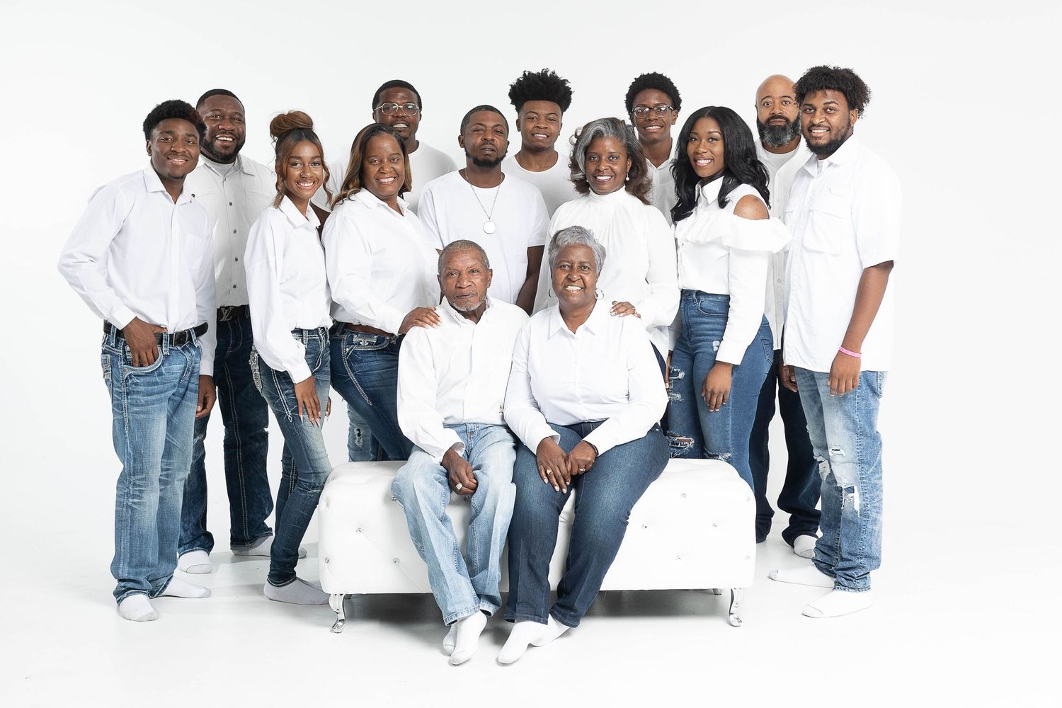 Large family group portrait with everyone wearing coordinated white tops and blue jeans.