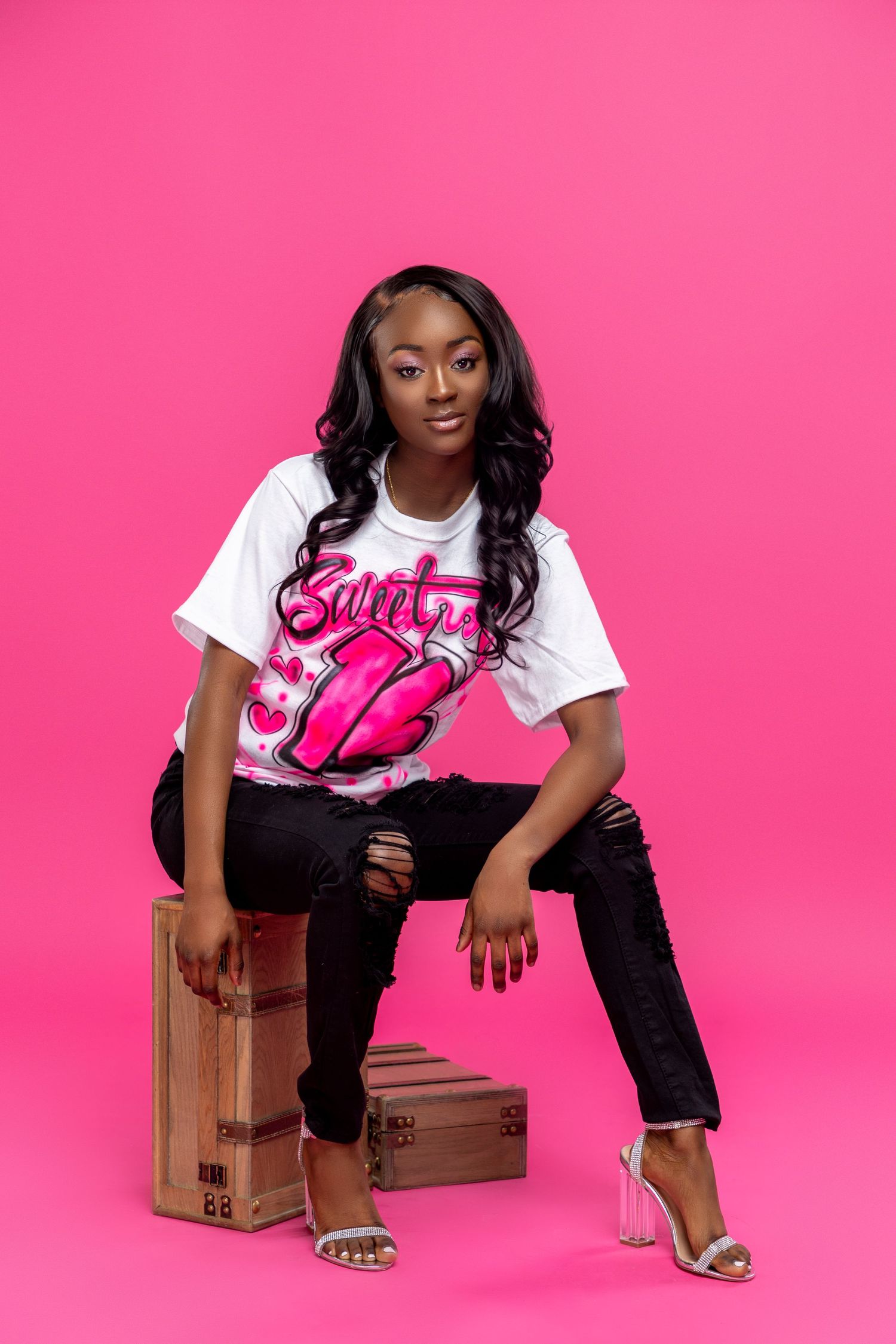 Casual portrait against pink background featuring white graphic t-shirt and stylish heels.