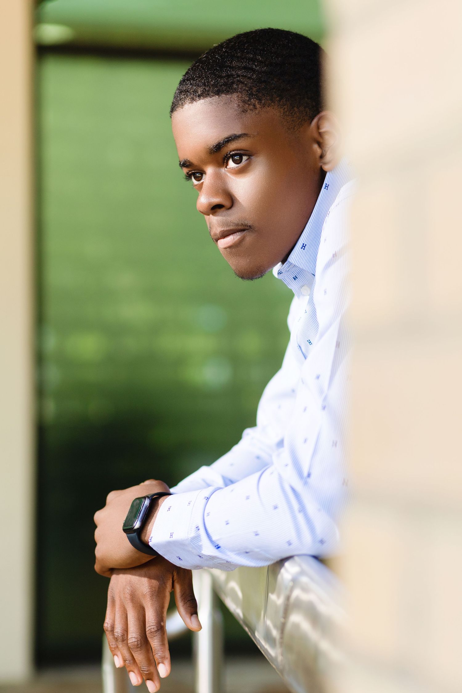 Professional leaning against railing in business casual attire.