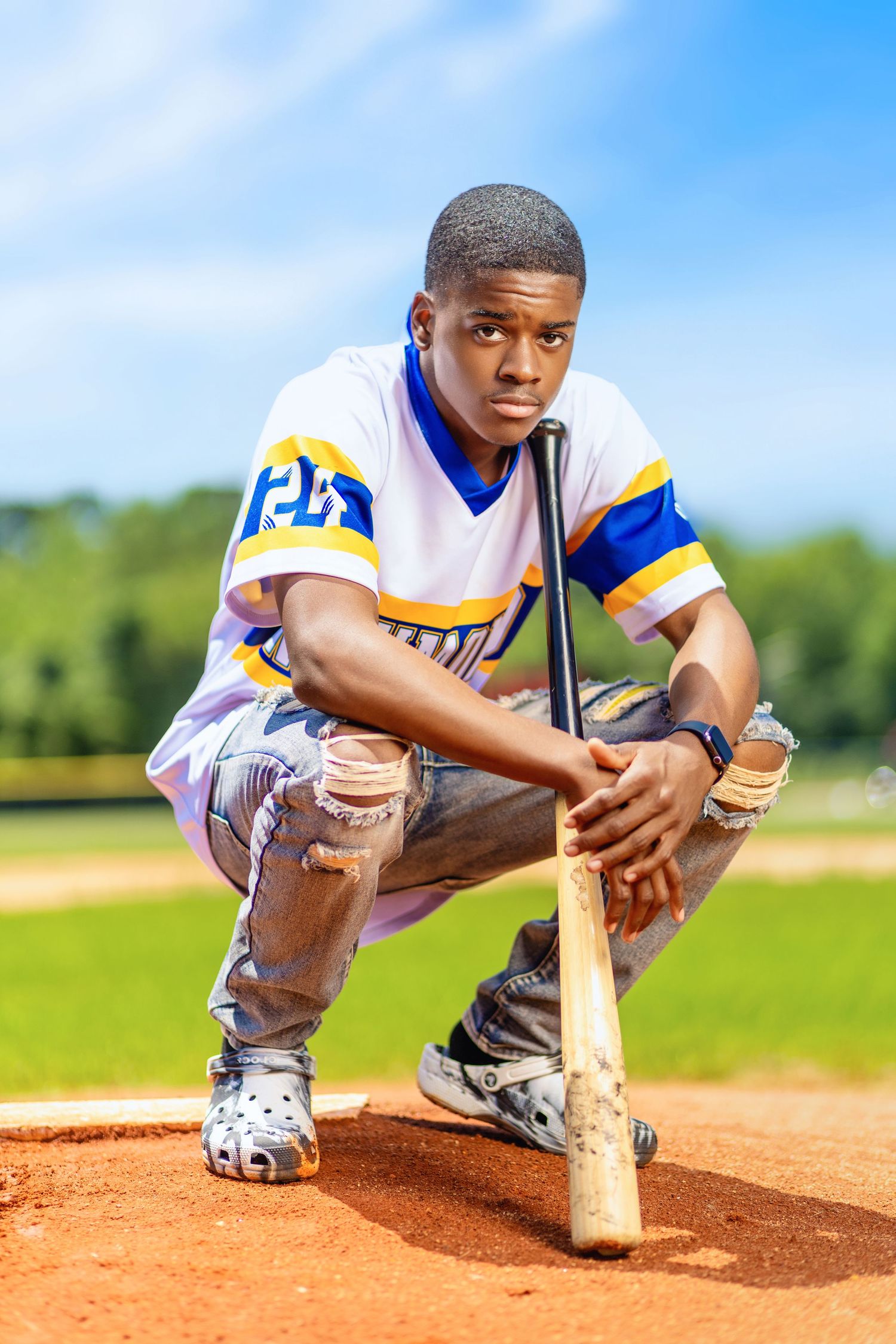 Baseball player in white and blue uniform crouching on pitcher's mound with bat.