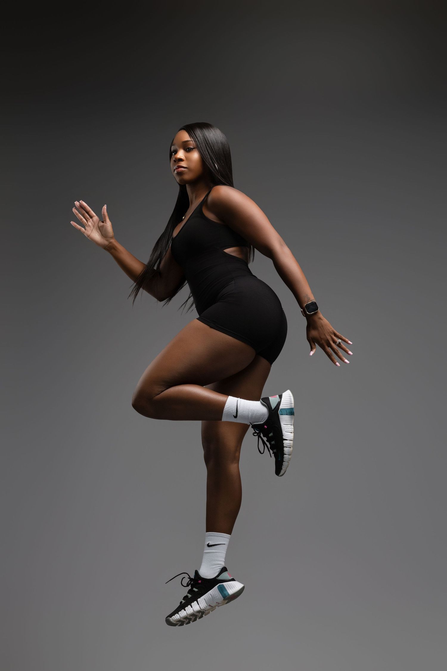 Dynamic action shot of an athlete jumping in black athletic wear against a dark background.