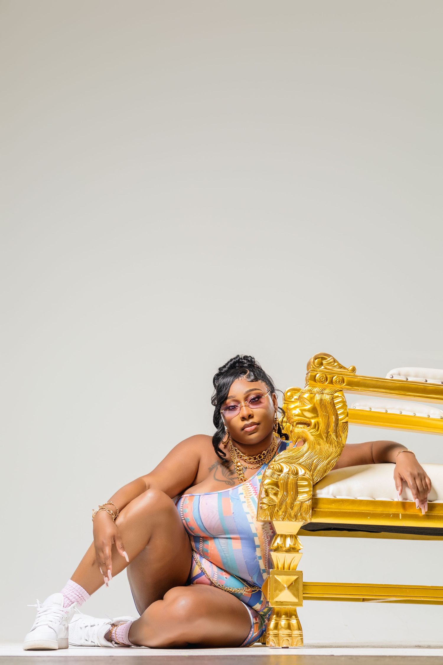 Studio fashion photo with someone posing next to an ornate gold frame in athletic wear.