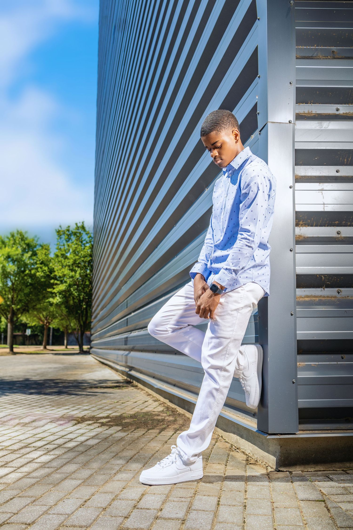 Stylish casual outfit with light blue shirt and white pants against modern architectural backdrop.