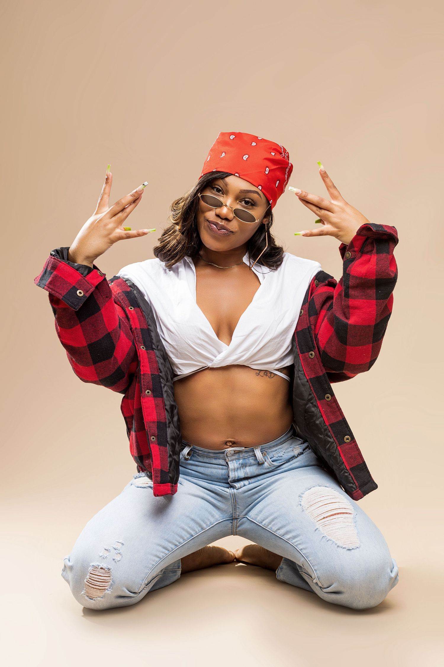 Casual style with red bandana, plaid shirt and ripped jeans in studio setting.