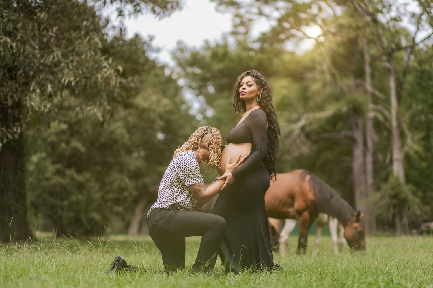 A romantic maternity photo session with horses grazing in the background.