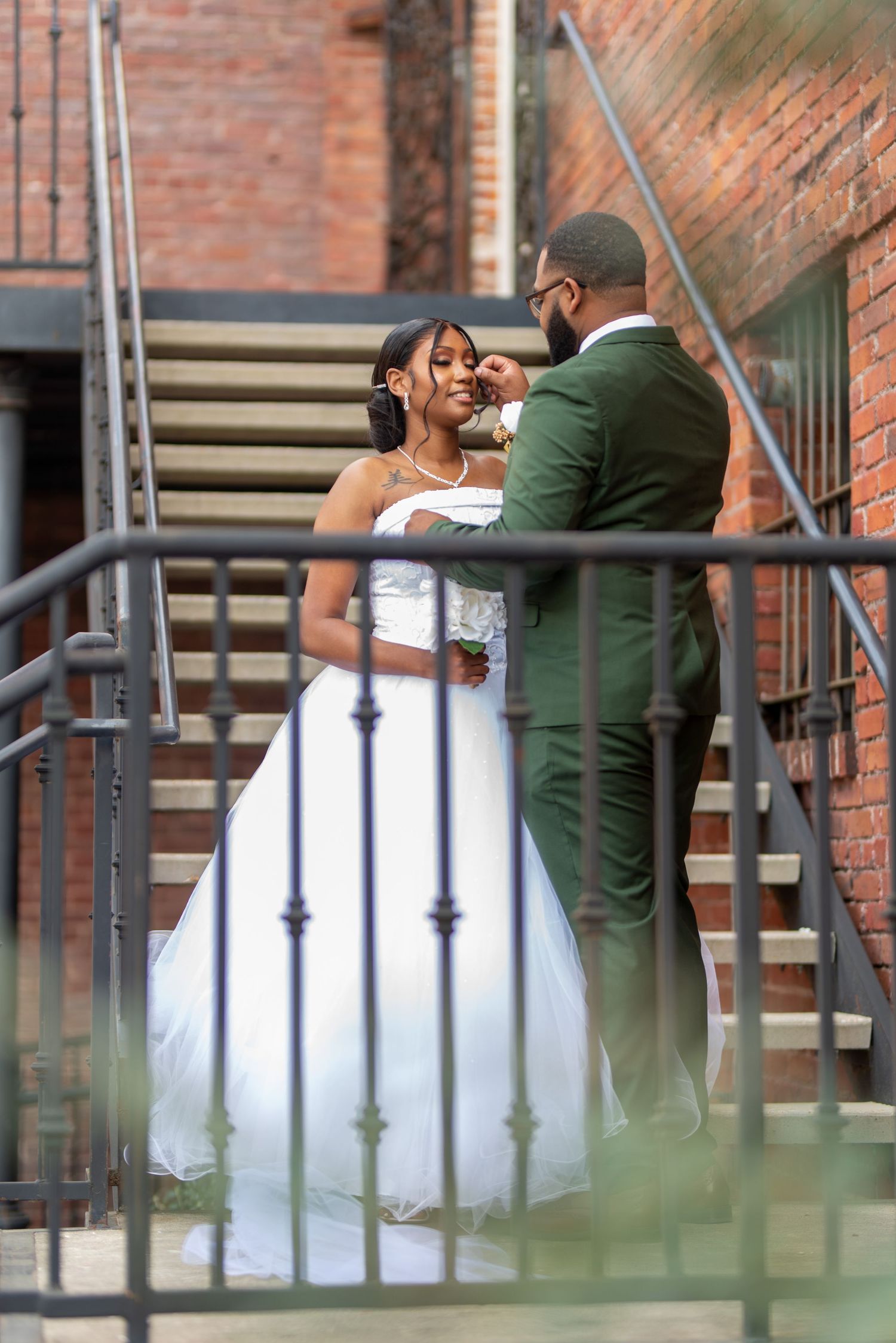 Tender moment between bride and groom on industrial staircase.