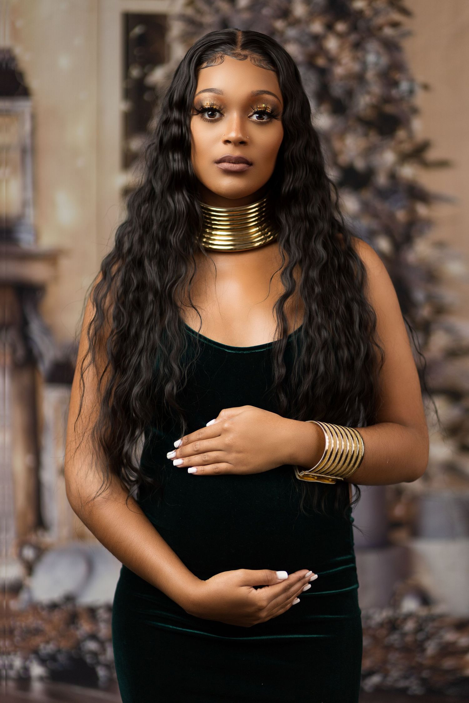 Elegant portrait in black velvet dress with gold statement jewelry and long wavy hair.