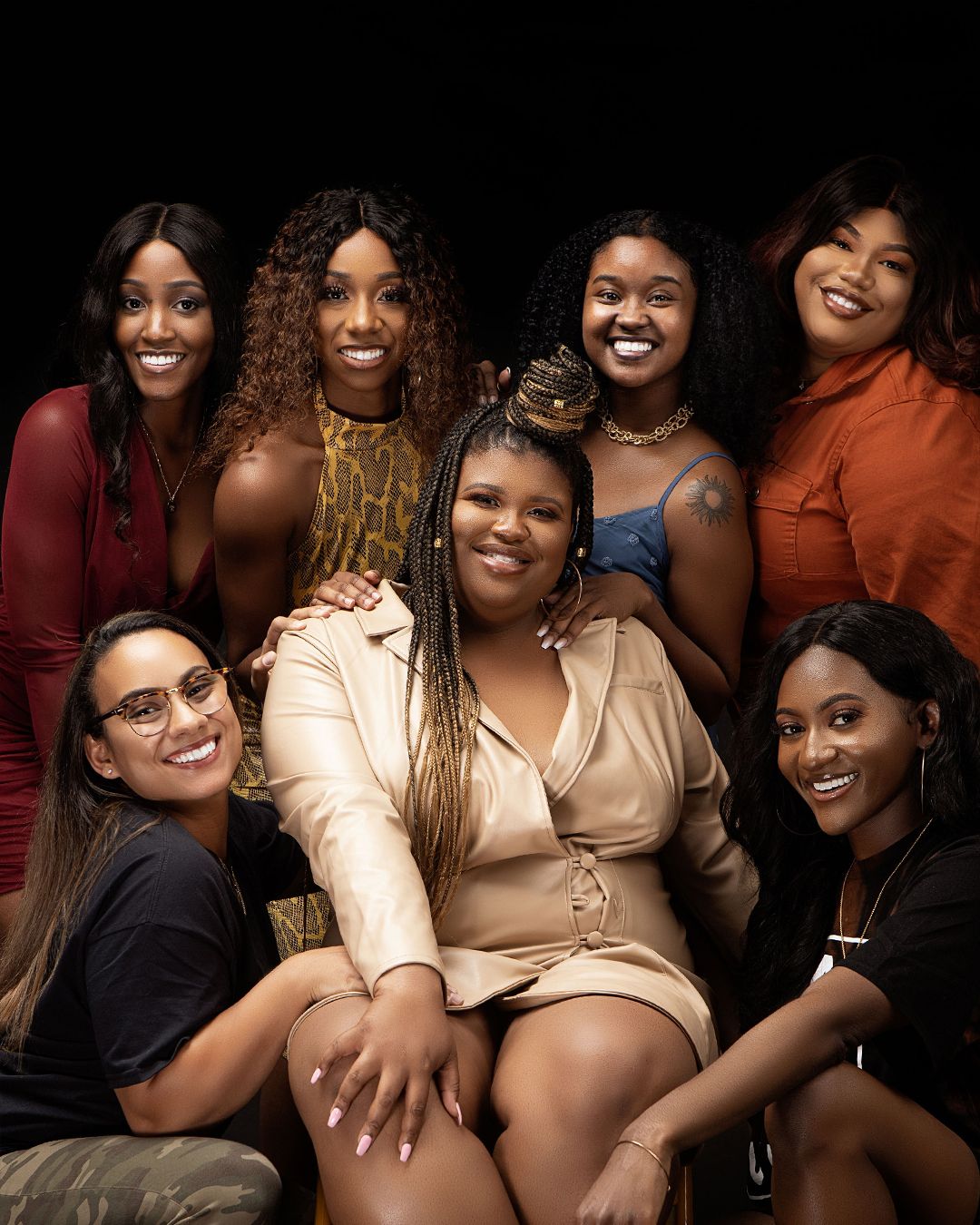 Group photo showing seven friends smiling and posing together in colorful outfits.