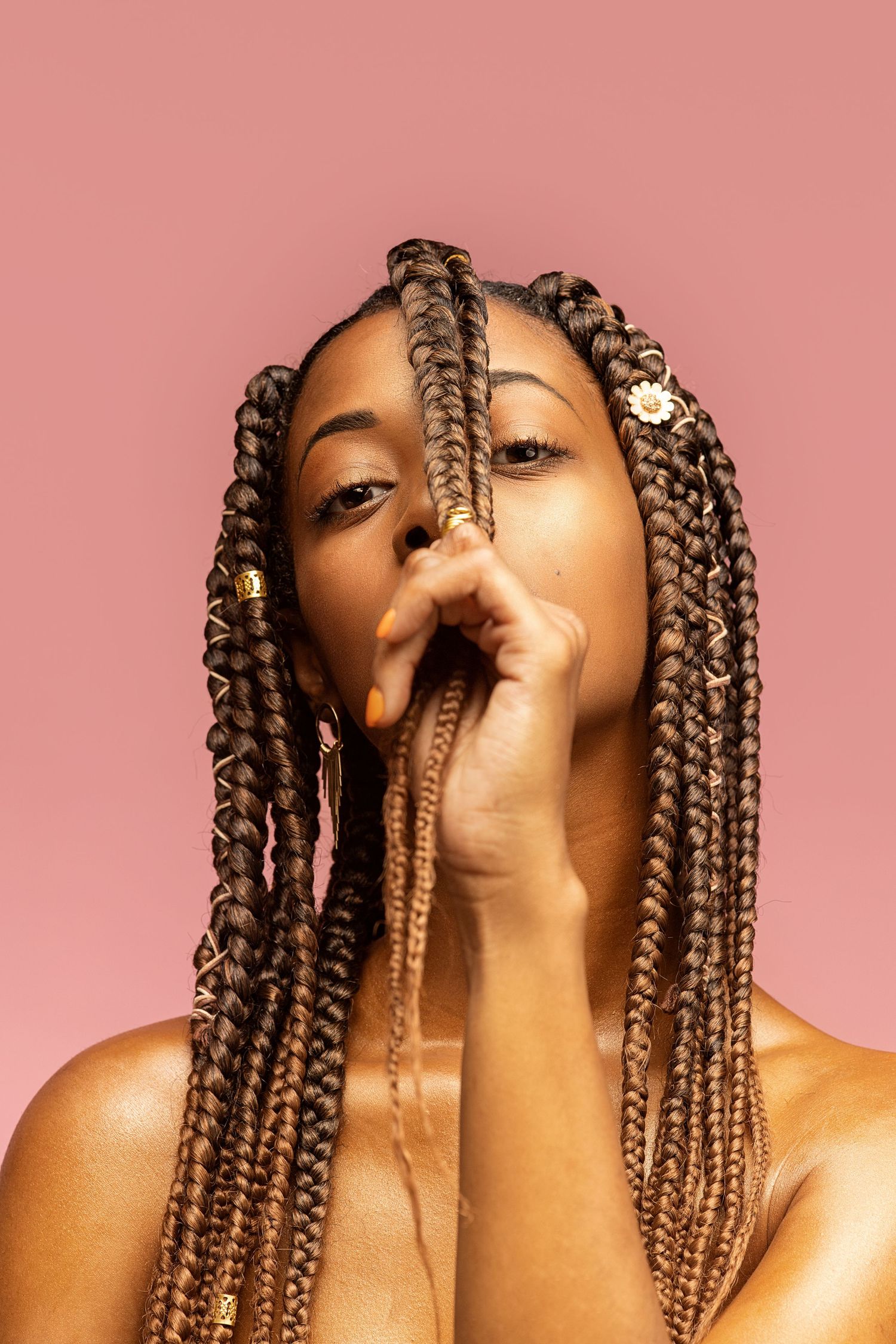 Creative beauty portrait with long braids against pink background.