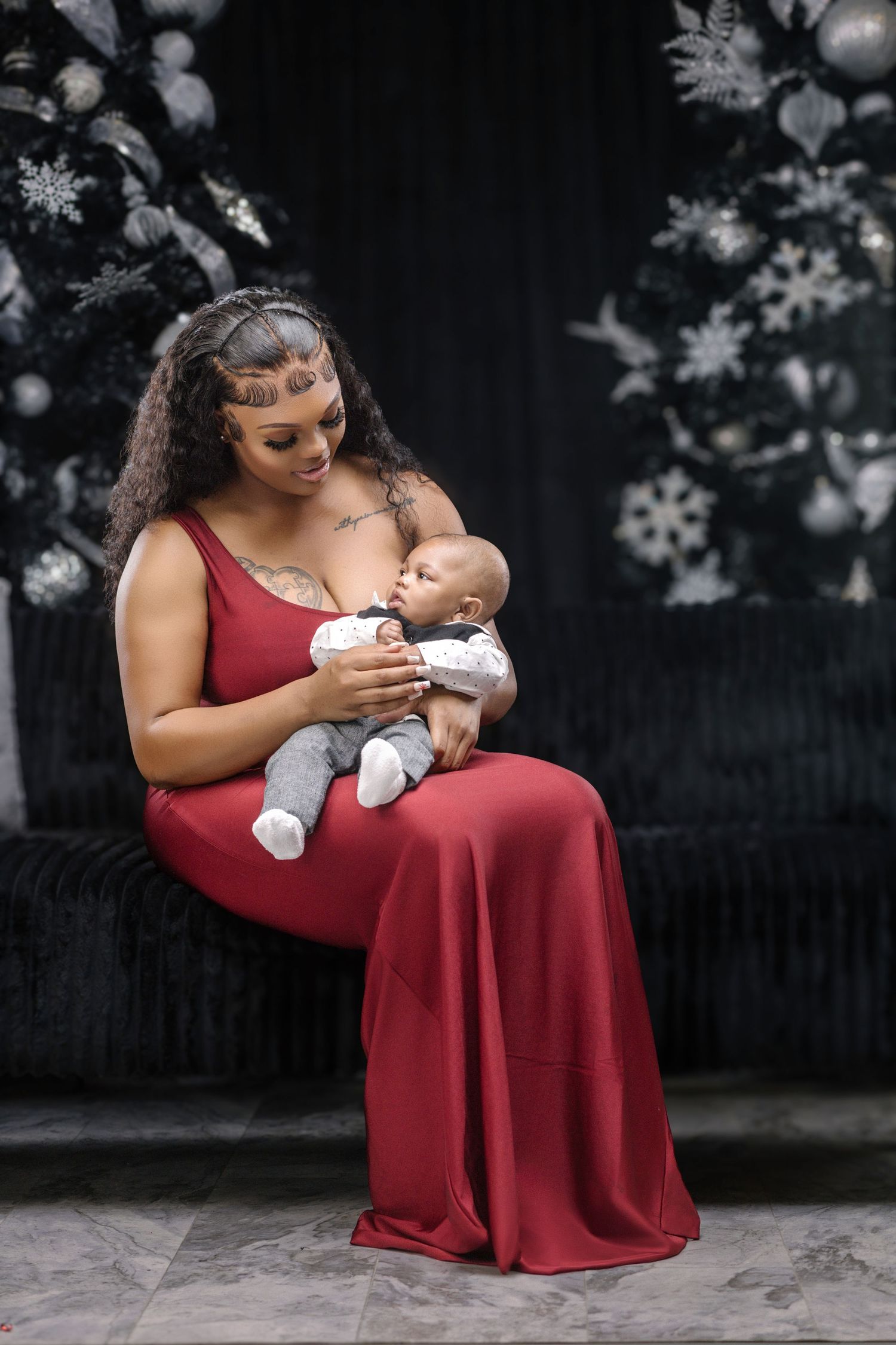Mother in red dress feeding baby during Christmas photo session.