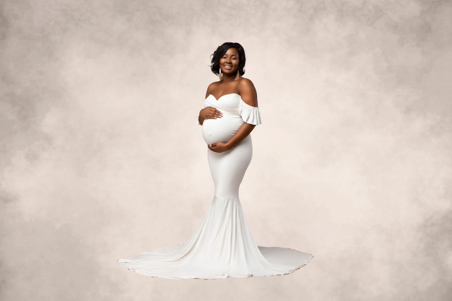 Elegant maternity photo featuring white mermaid dress against textured backdrop.