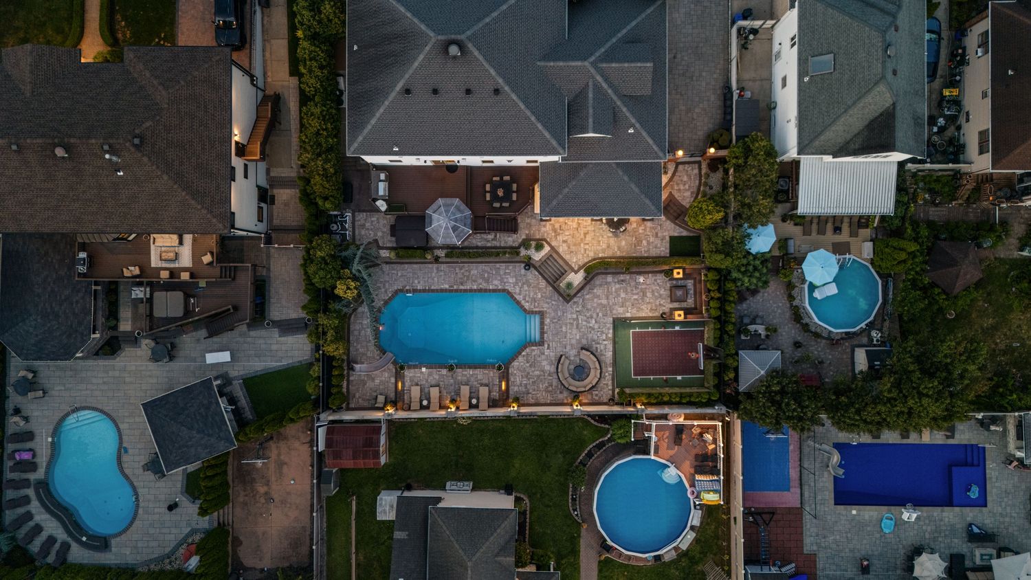Aerial view of residential neighborhood showing multiple backyard swimming pools.