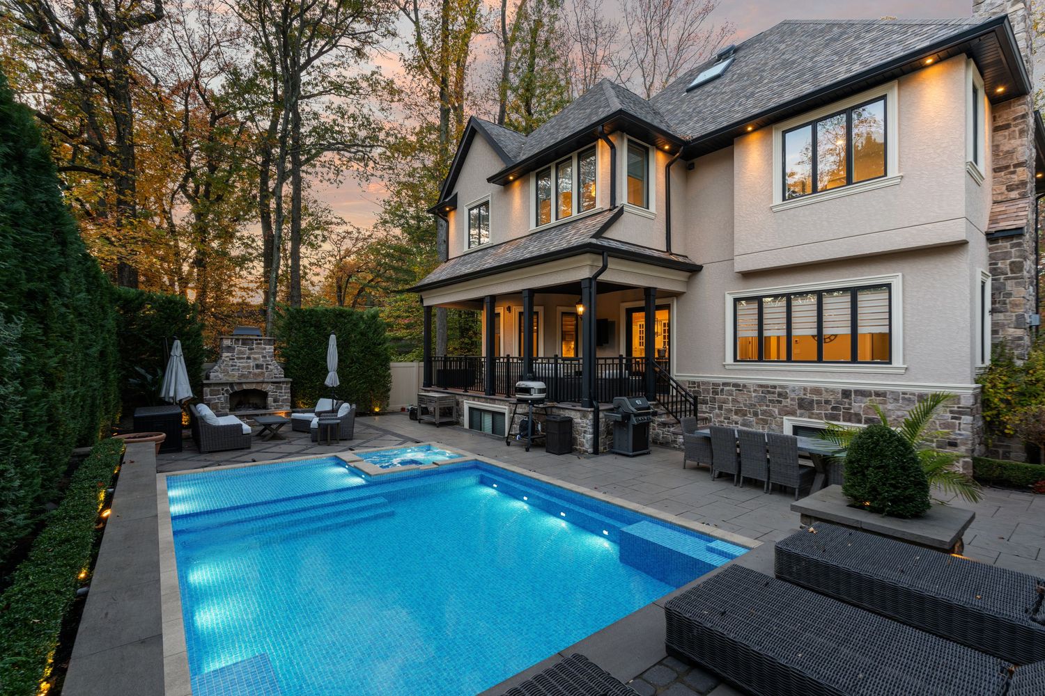 Modern luxury home exterior with swimming pool and stone accents at twilight.