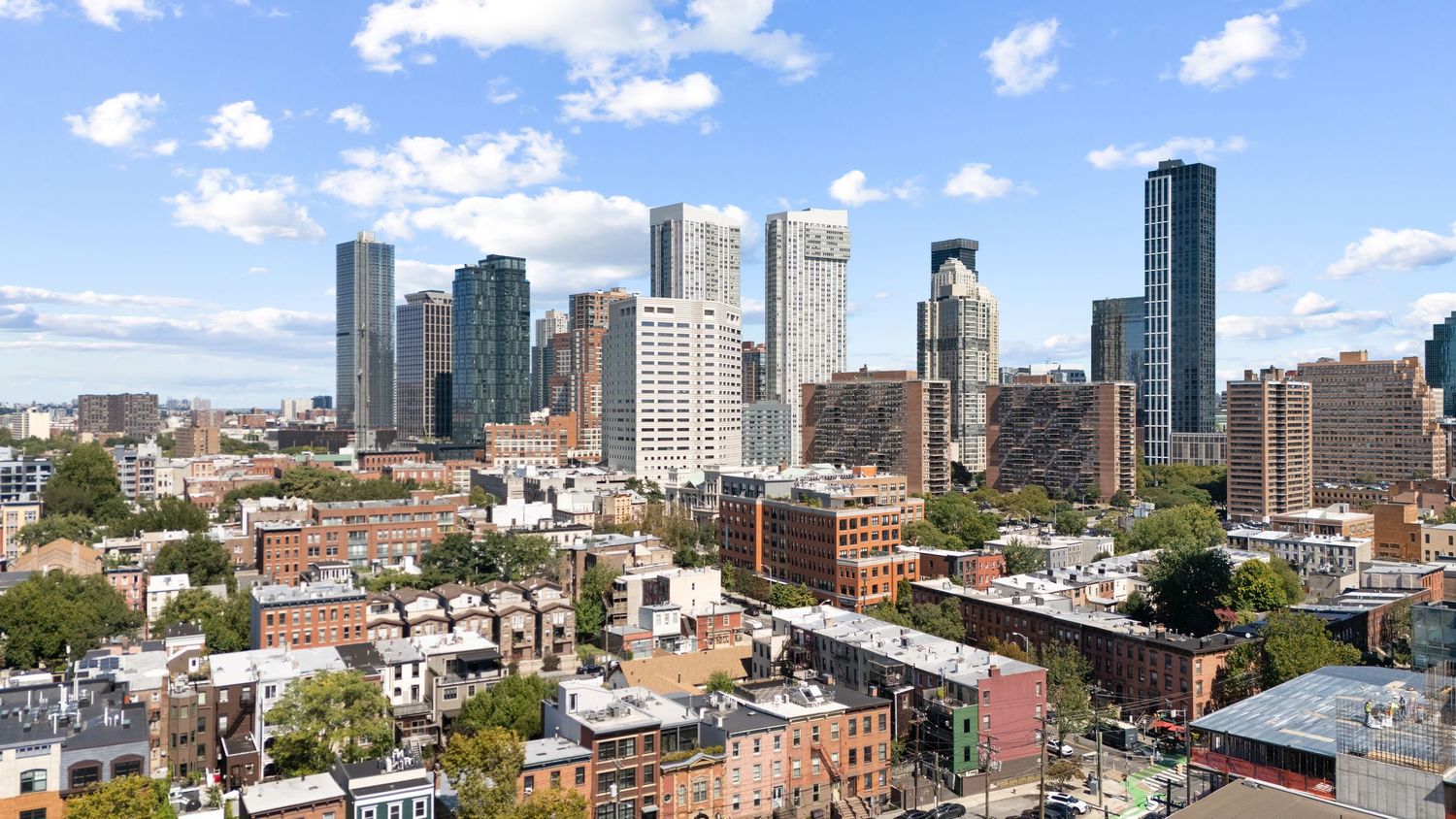 Panoramic cityscape view of downtown skyscrapers and urban buildings against blue sky.