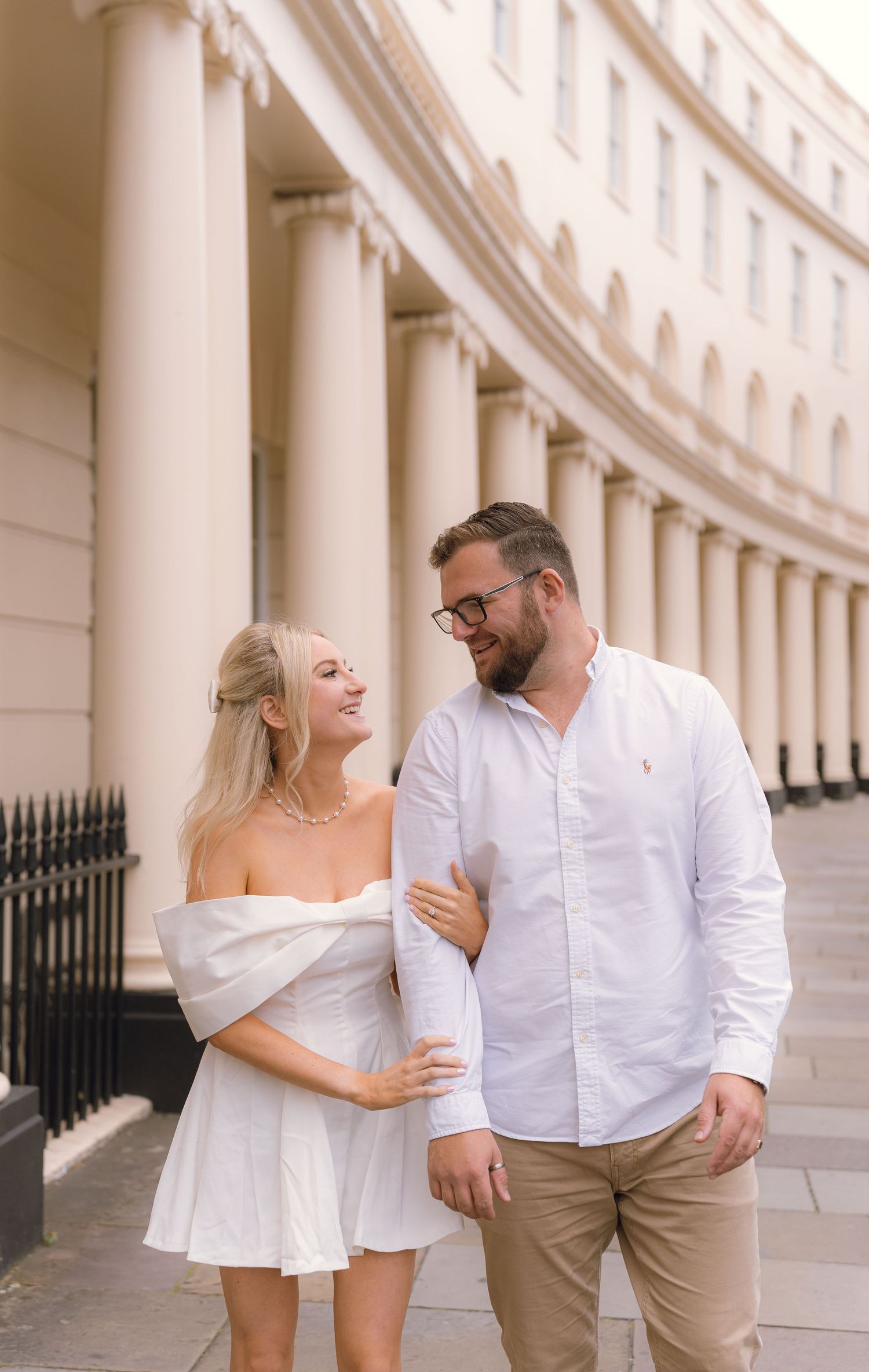 Romantic couple shares a tender moment by elegant white columns of historic Georgian architecture in London.