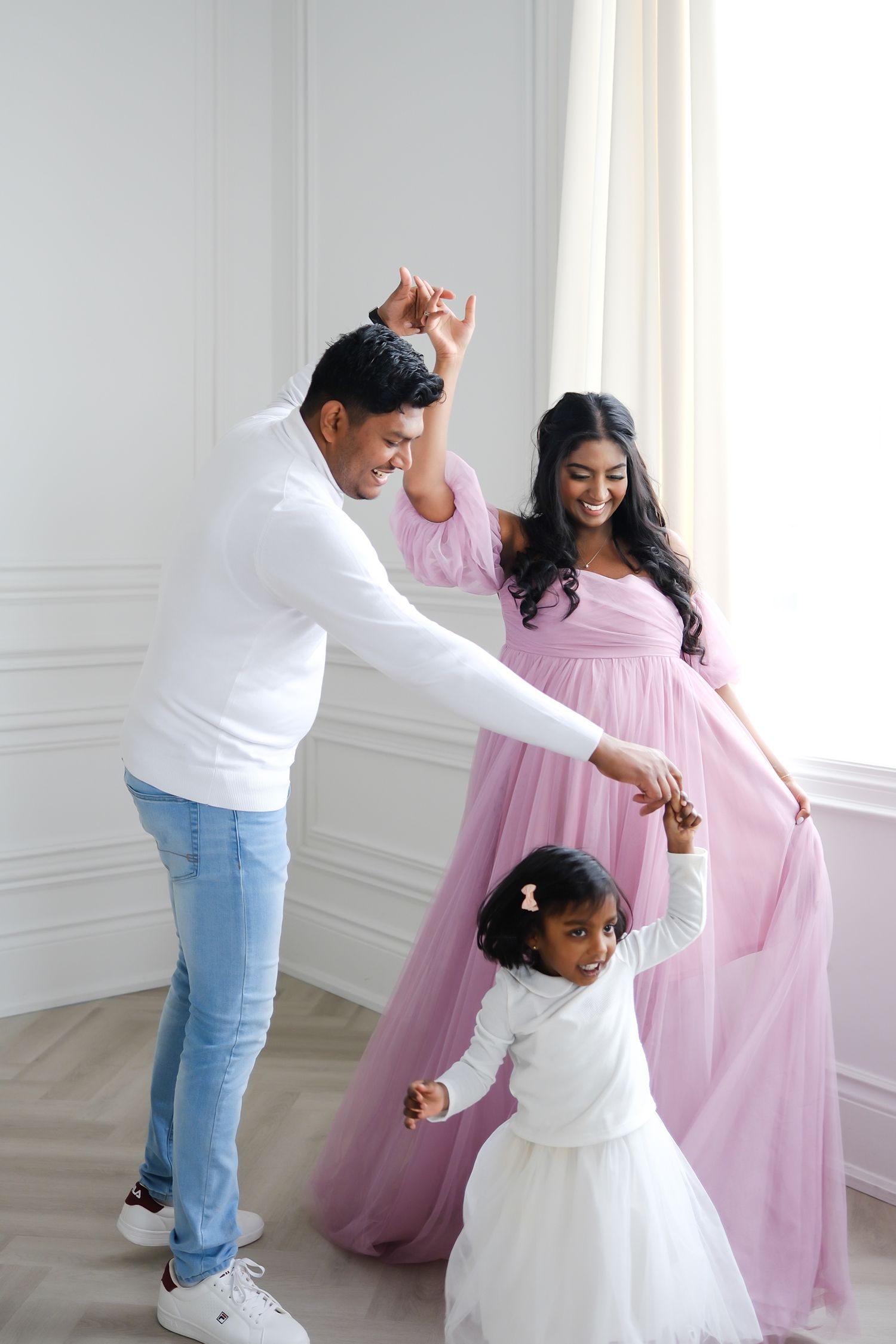Family dancing together in bright room with woman in flowing pink dress. Toronto, photographer, majestystudios, maternity, portrait
