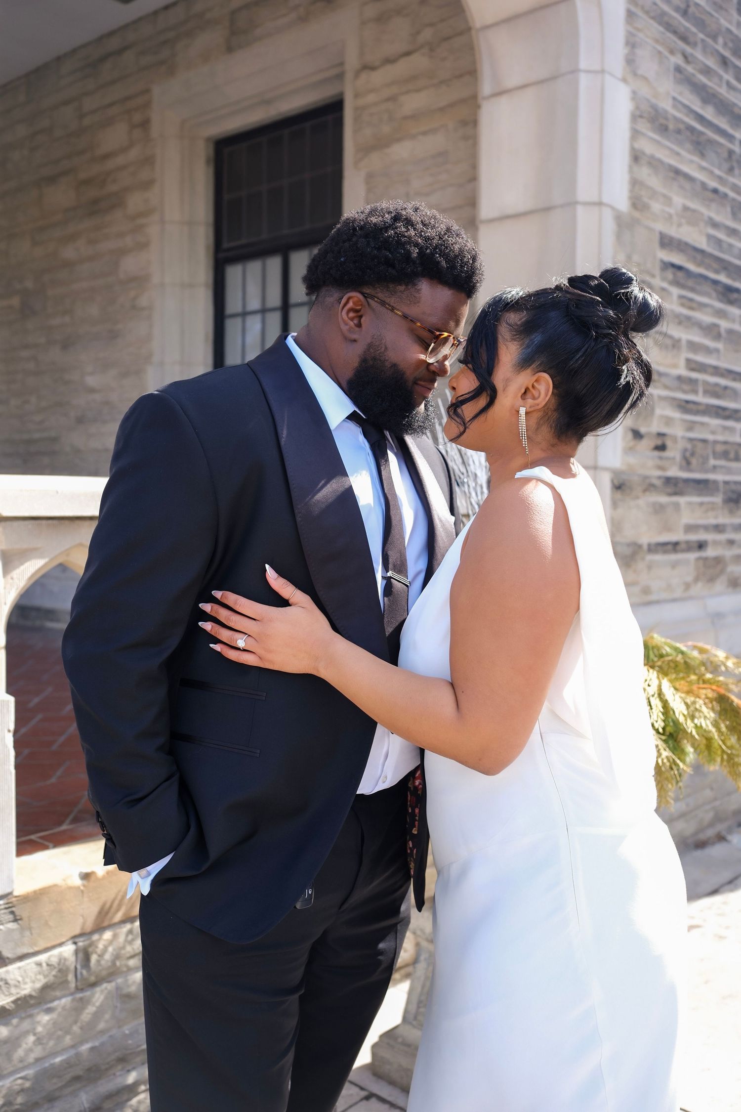 A romantic wedding couple share an intimate moment outside a stone building on their special day.