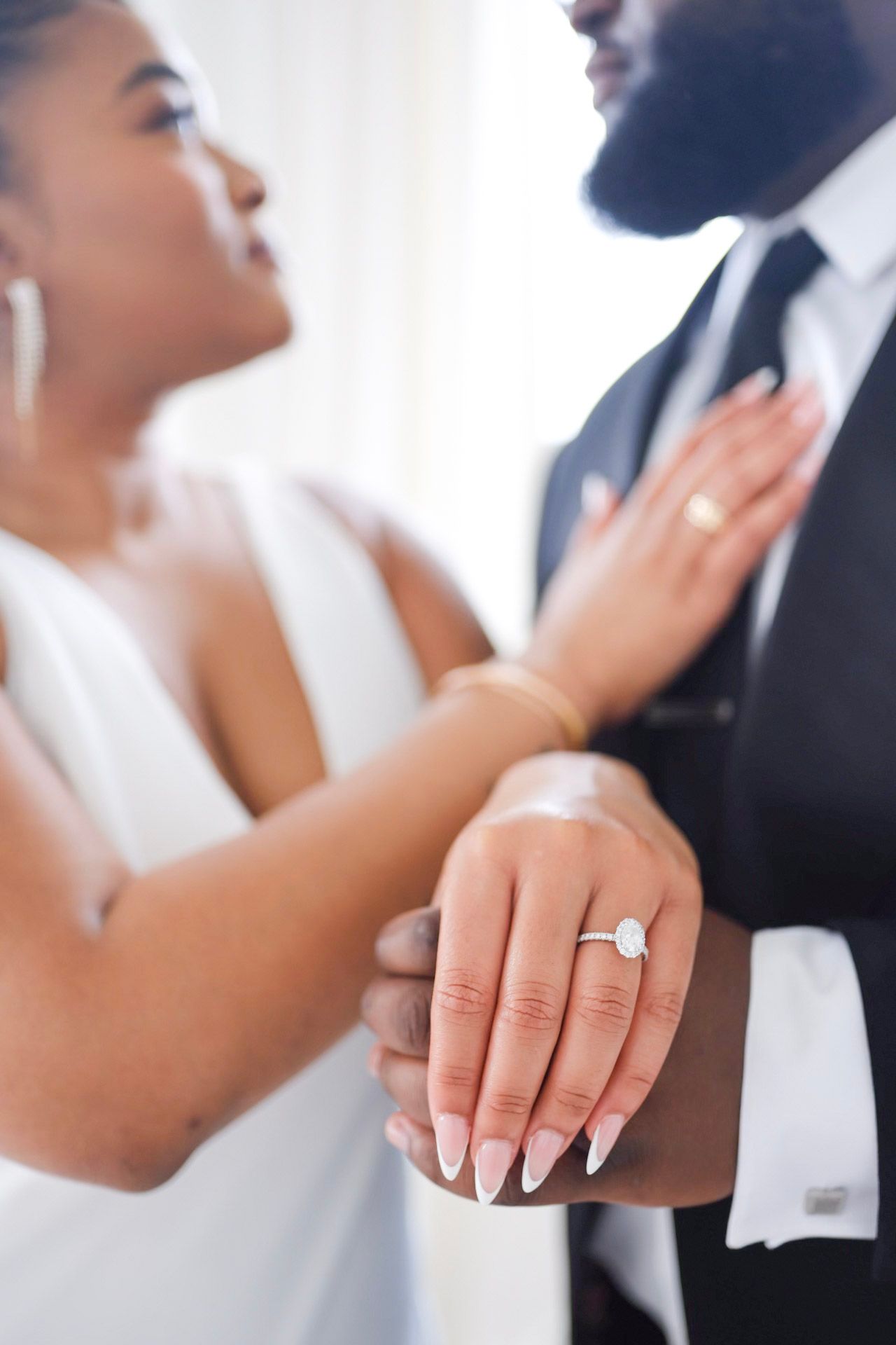 Close-up of hands showing off engagement ring during romantic wedding moment in dreamy soft focus.