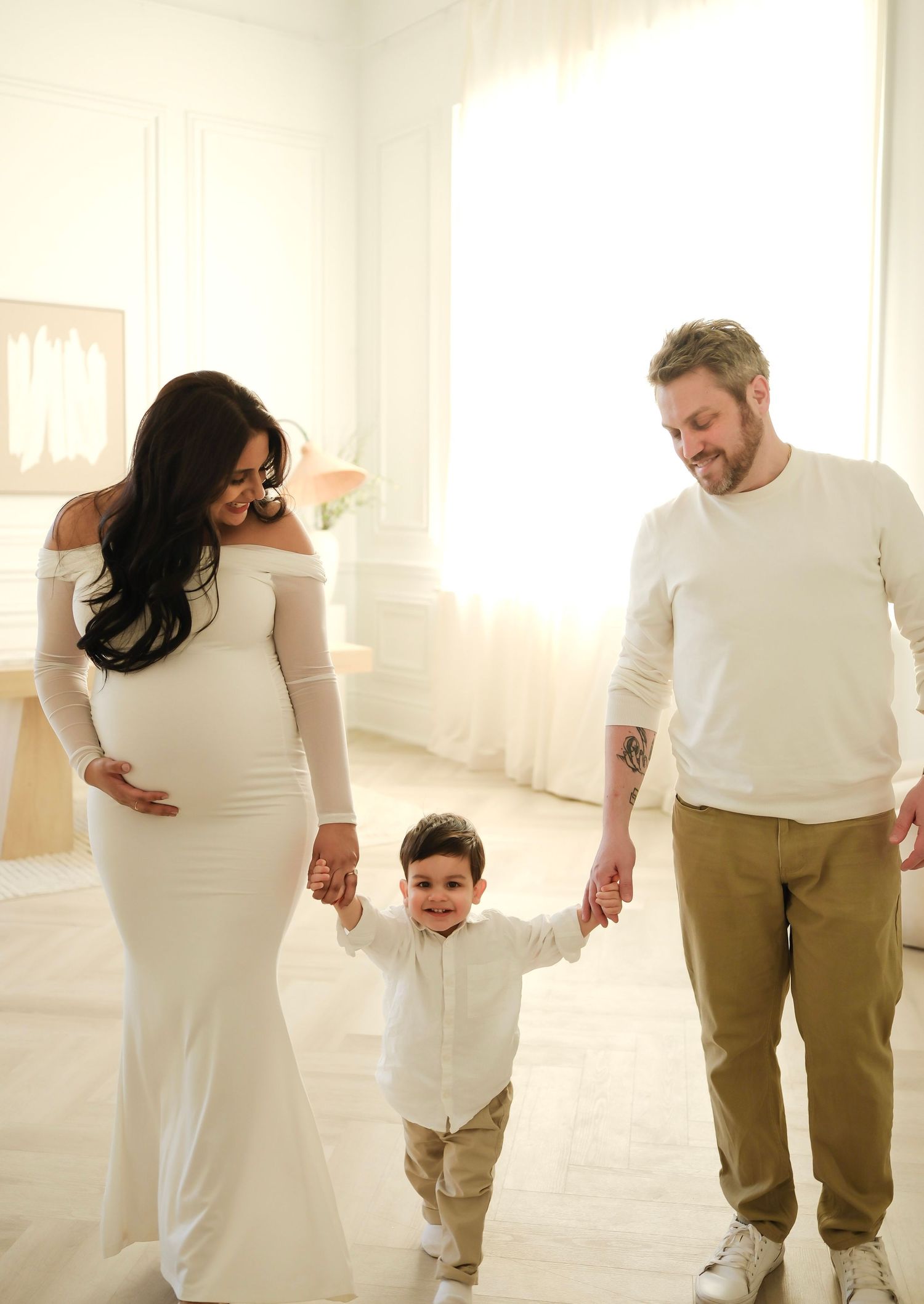 Family holding hands in sunlit white room with maternity photo session. Toronto, photographer, majestystudios, greater toronto area, family