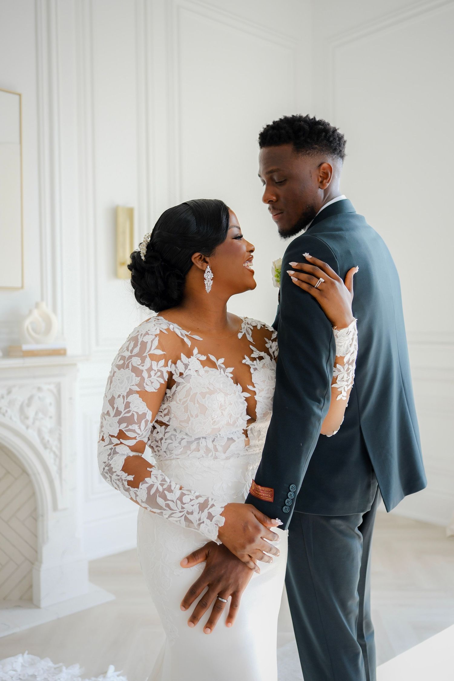 A couple shares an intimate moment on their wedding day in an elegant white room with ornate details.