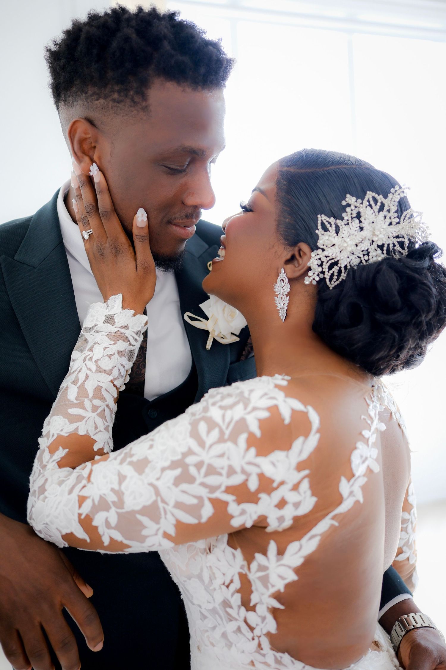A romantic wedding portrait shows a tender moment between newlyweds with beautiful lace details and elegant formal attire.